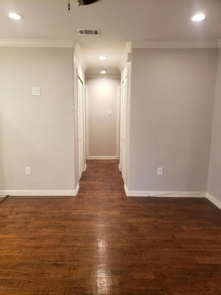 Wood-finish flooring, recessed lighting, crown molding, and two louvered closet doors