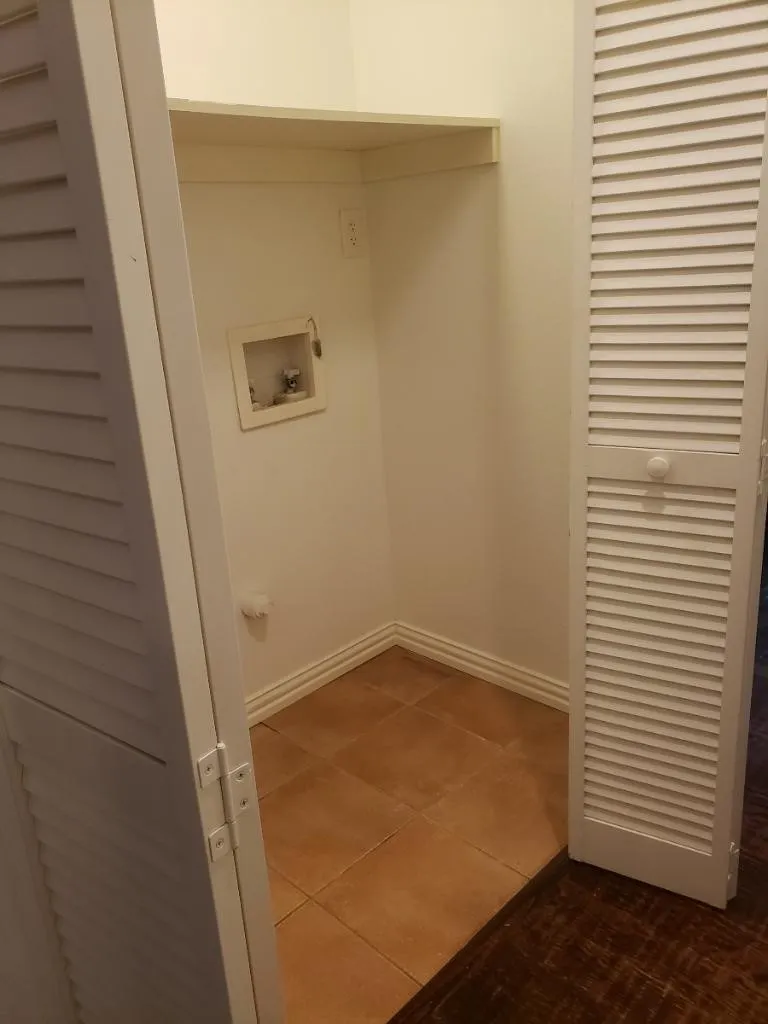 Laundry area featuring a built-in shelf, tile flooring, and louvered bi-fold doors