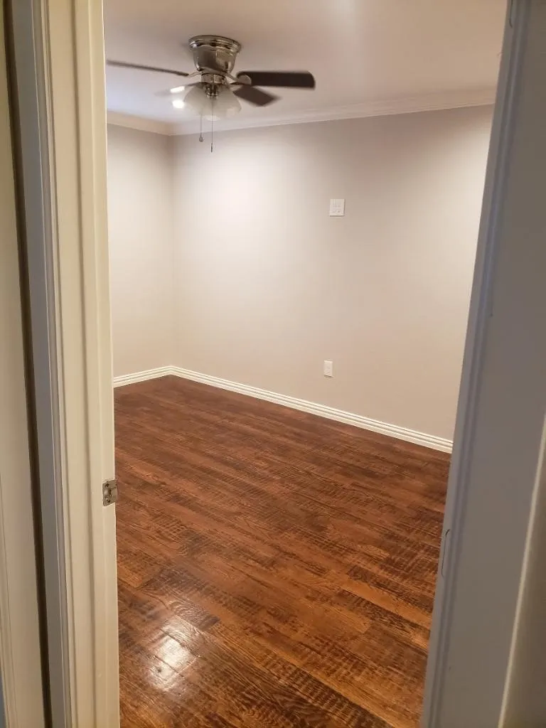 Wood-finish flooring, ceiling fan with light fixture, and crown molding