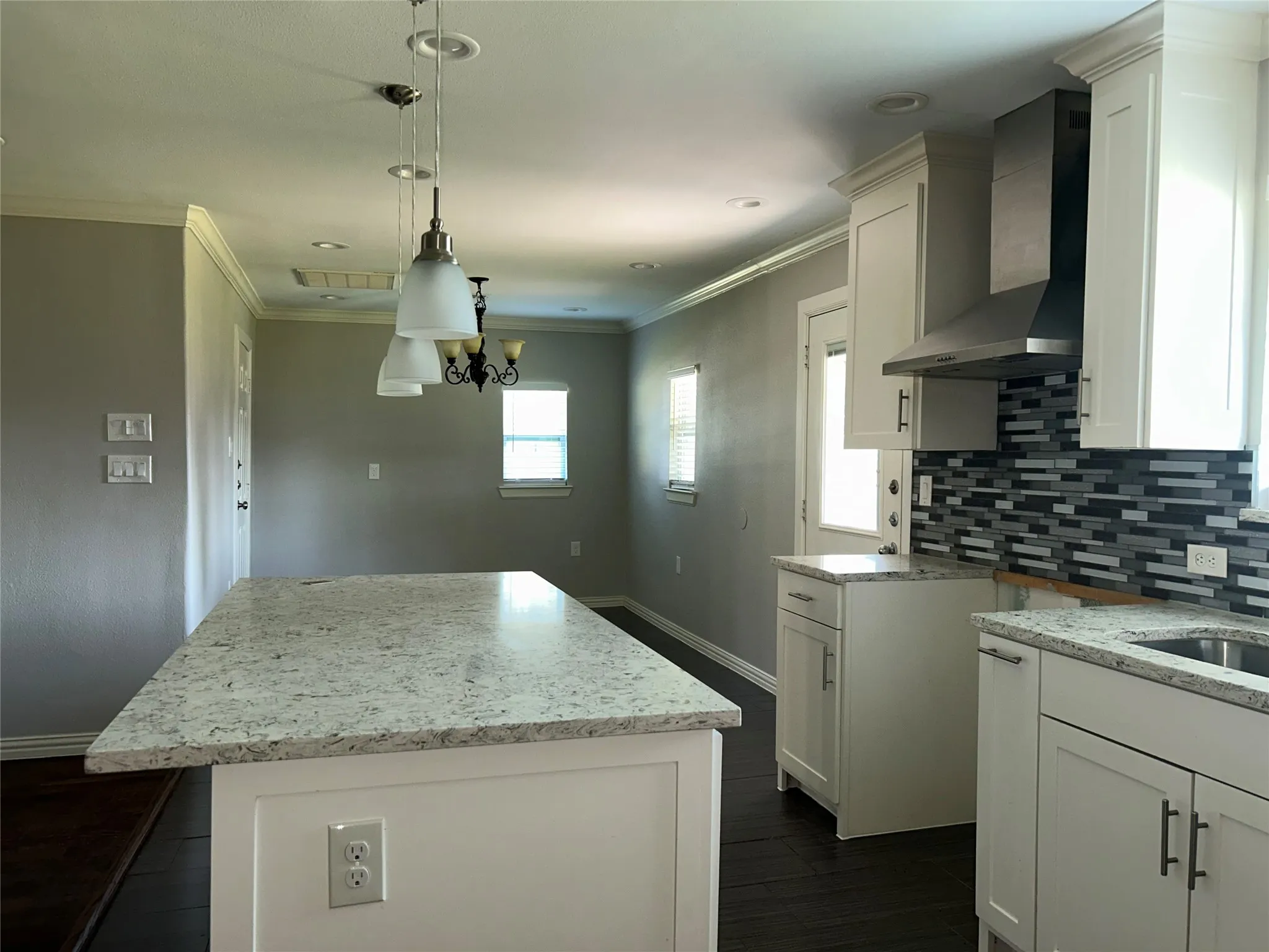 Kitchen featuring white cabinetry, stone countertops, dark wood-finish flooring, a mosaic tile backsplash, and stainless steel range hood