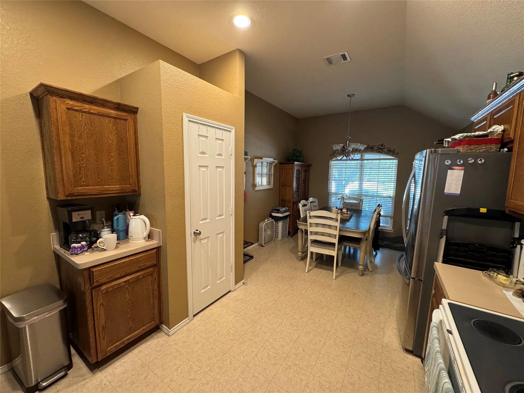 Kitchen and dining area featuring wood cabinetry, stainless steel refrigerator, and recessed lighting