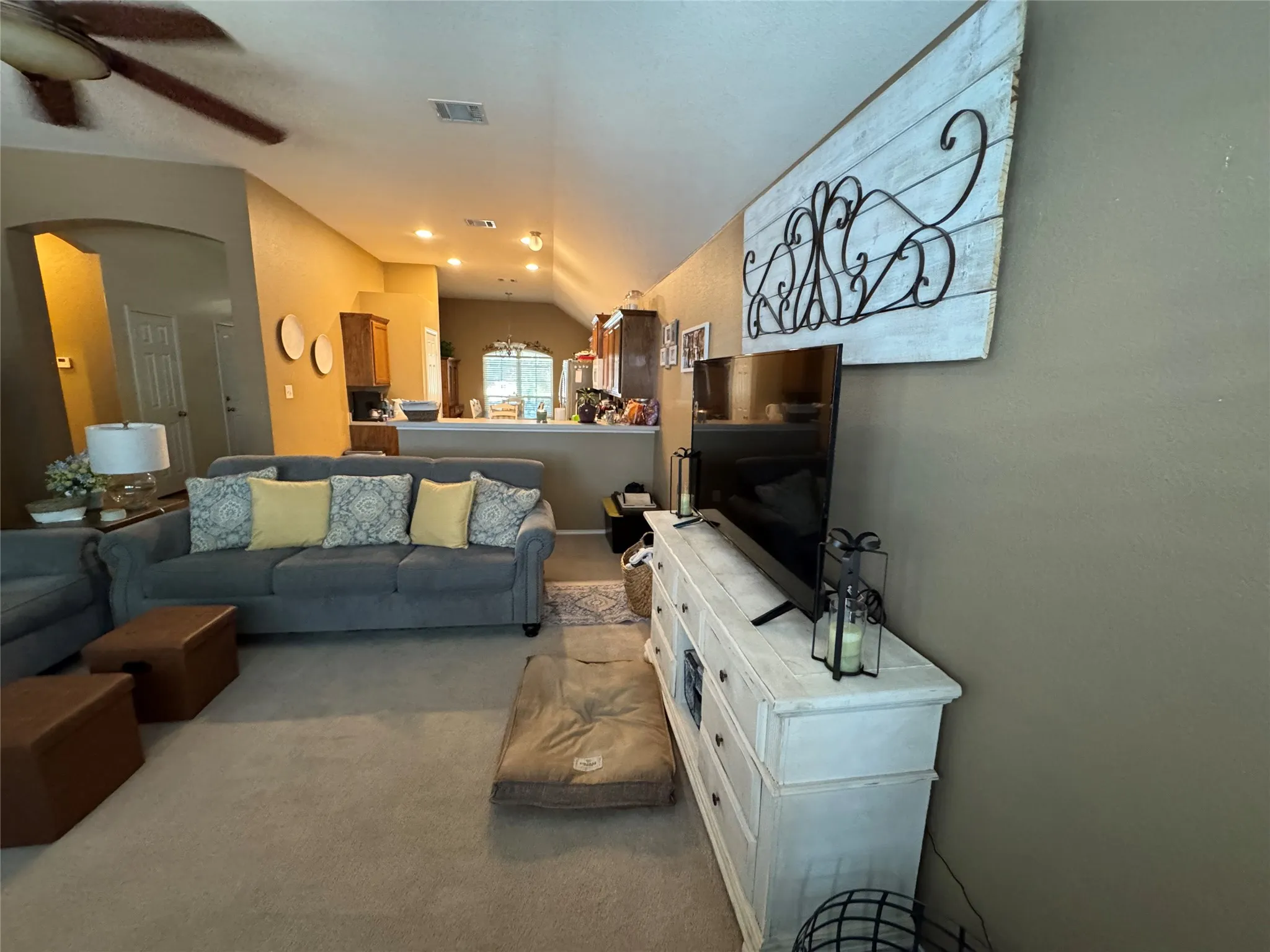 Carpeted living area with a ceiling fan, recessed lighting, and a partial wall separating spaces