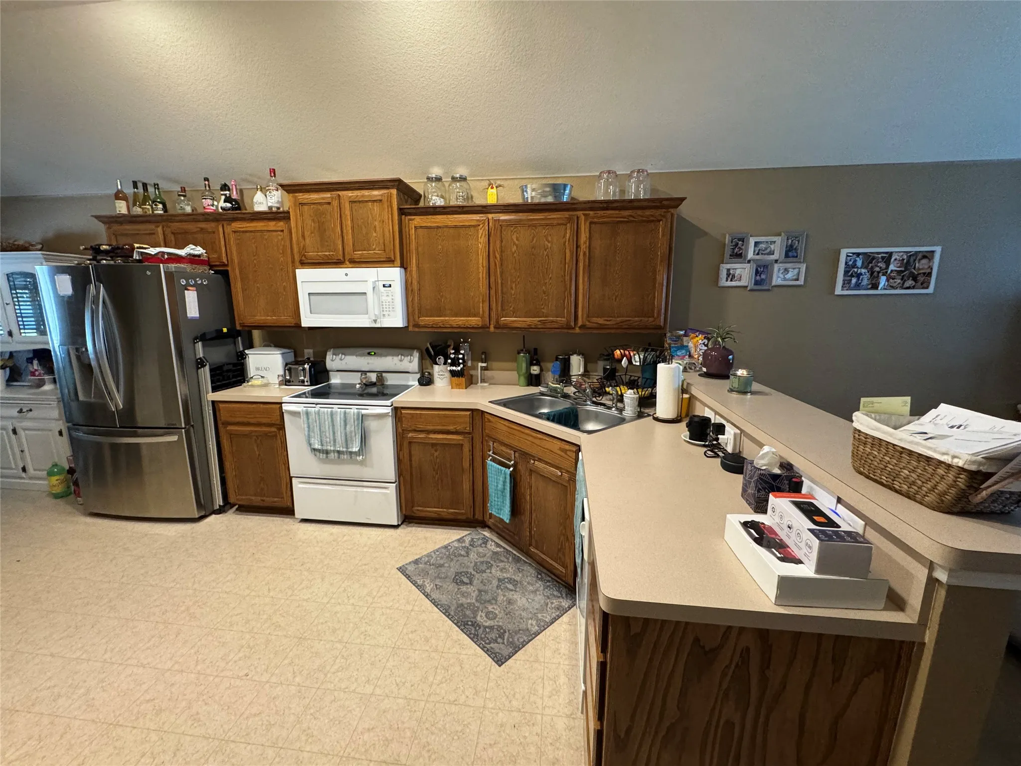 Full kitchen with wood cabinetry, stainless steel refrigerator, white oven, and white microwave