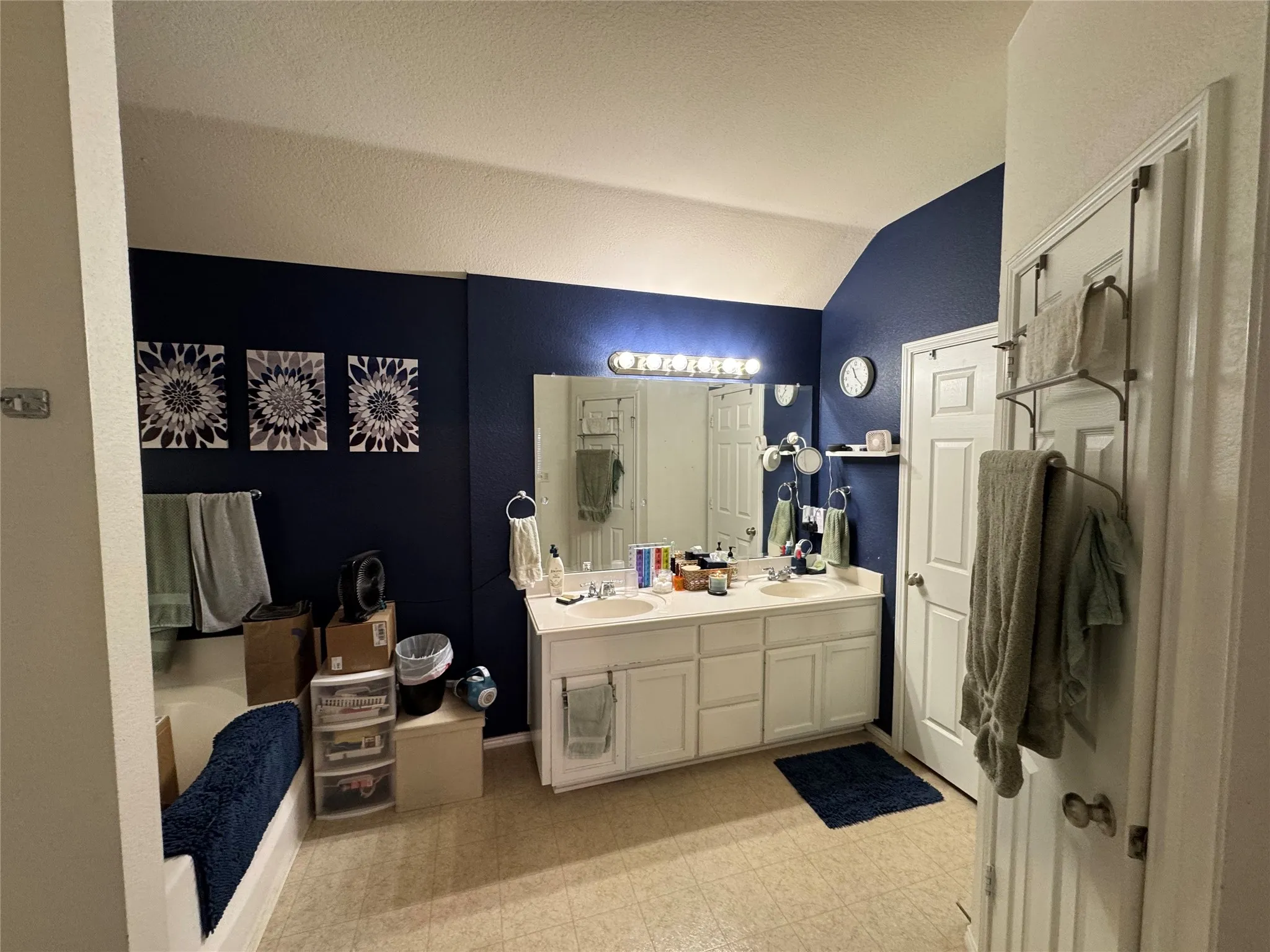 Dual vanity with white cabinetry, wall-mounted mirror, and overhead lighting