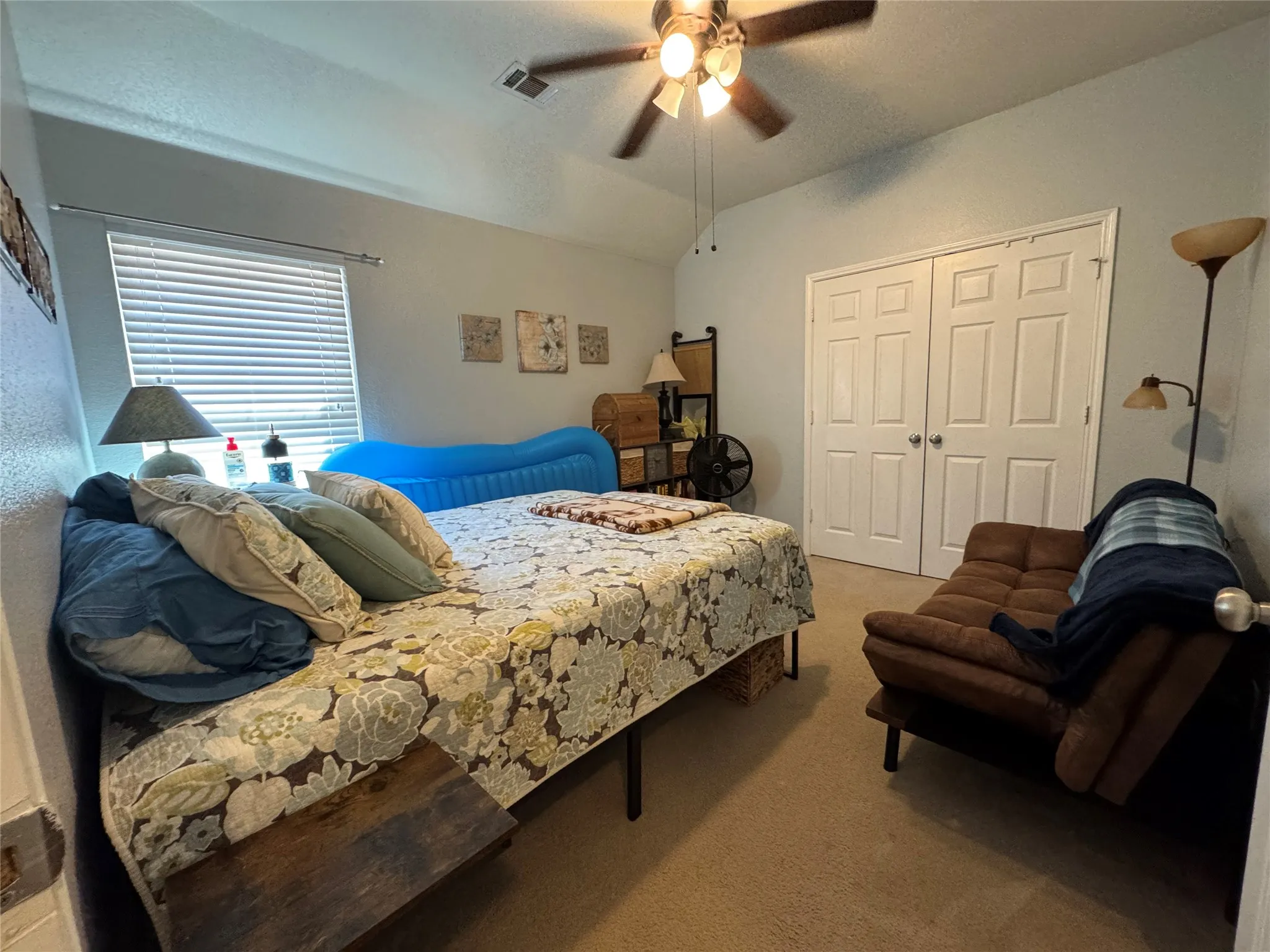 Recessed window with blinds, ceiling fan with light fixture, carpeted flooring, and double bi-fold closet doors