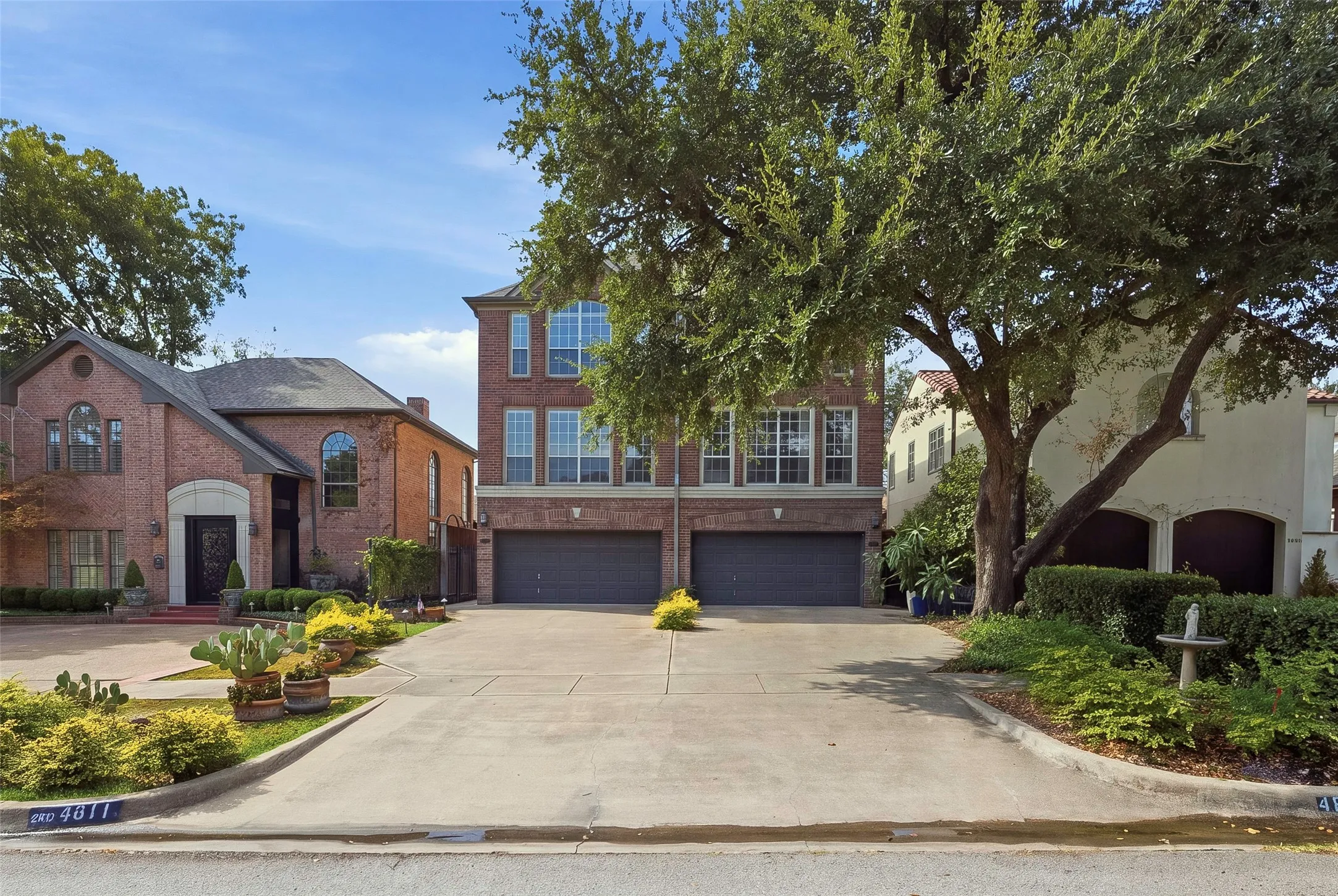Brick exterior, multi-story facade, attached garage, concrete driveway, established landscaping