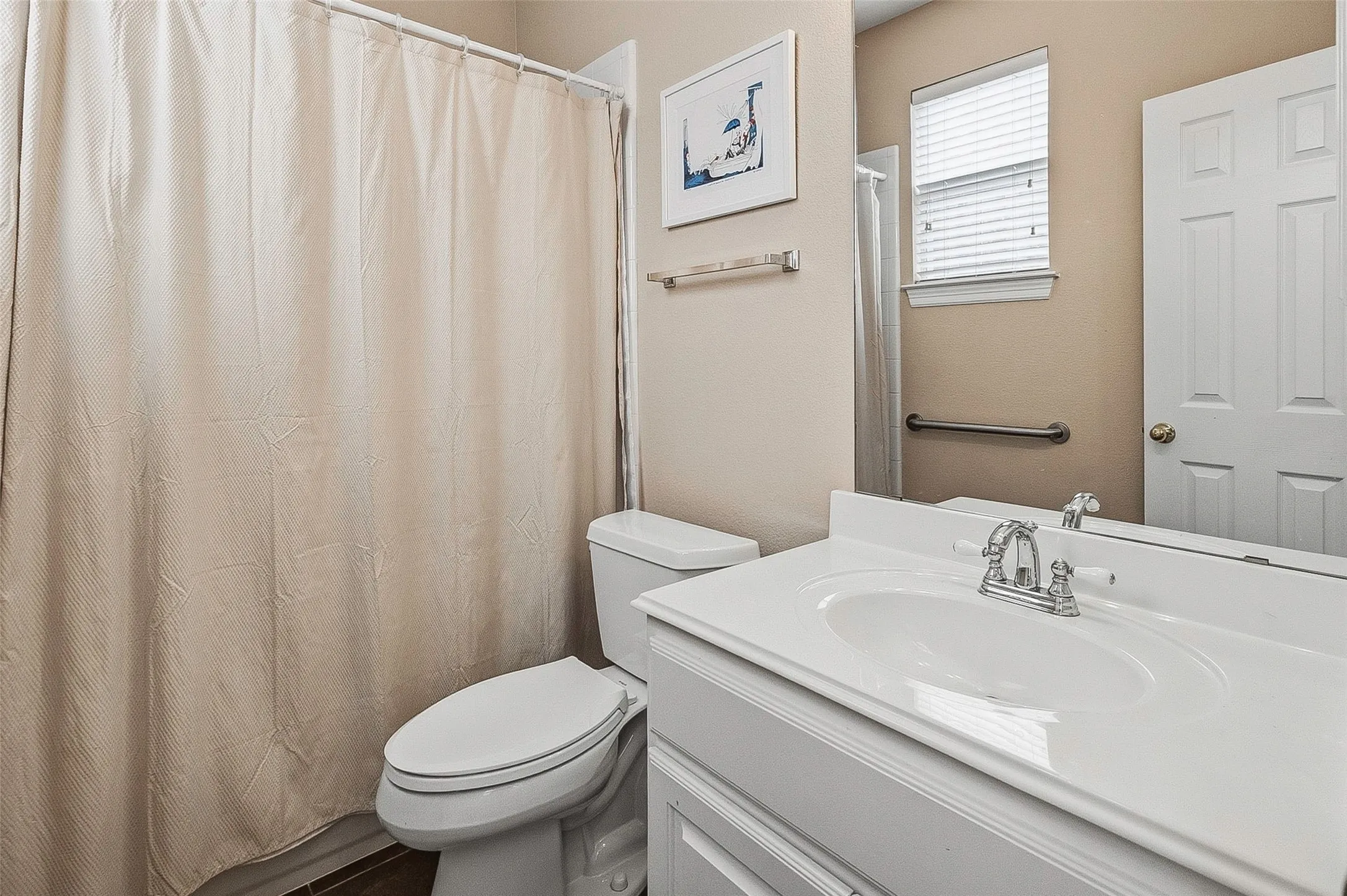 Bathroom featuring a single vanity with an integrated sink, chrome faucet, and a toilet