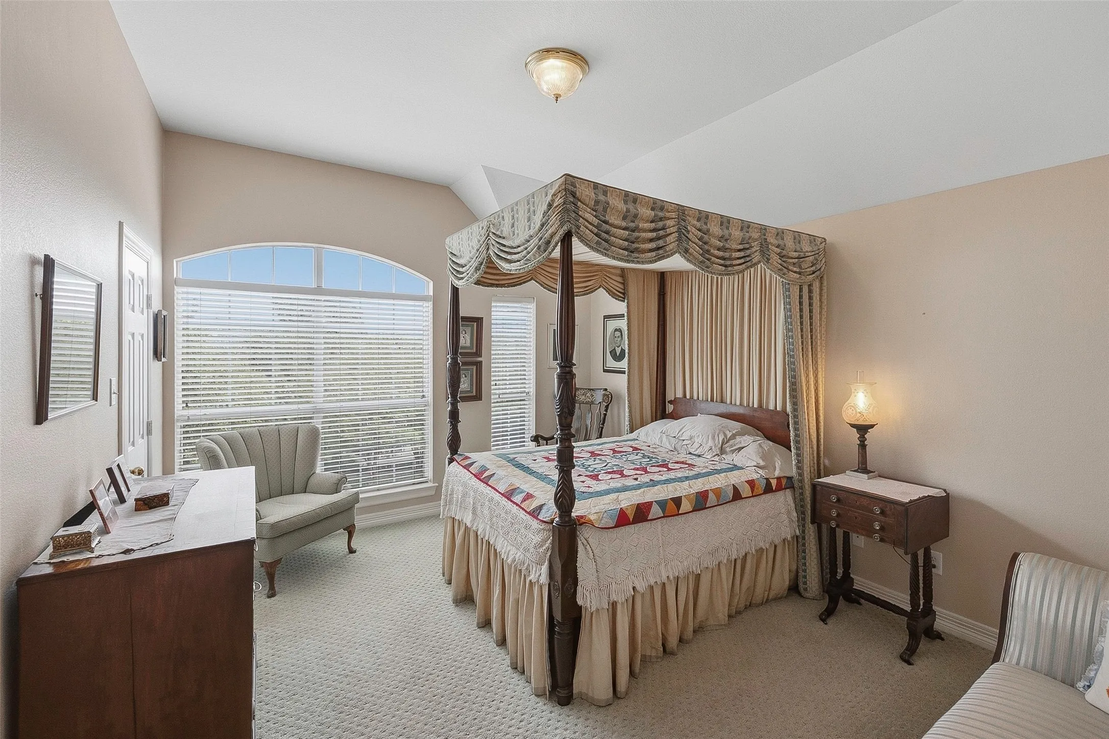 Room featuring a vaulted ceiling, arched window, and neutral wall tones