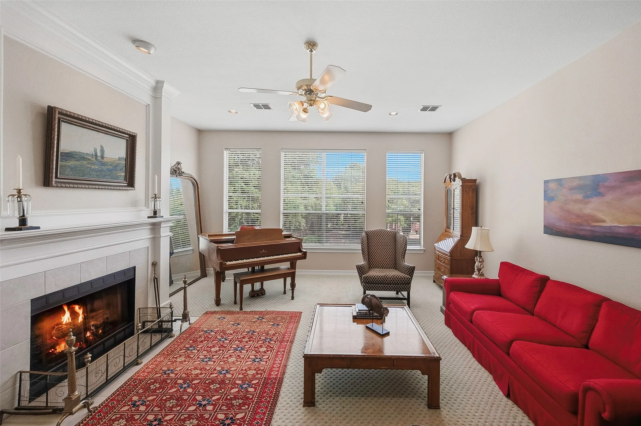 Living area featuring a fireplace with a stone surround, crown molding, and a ceiling fan