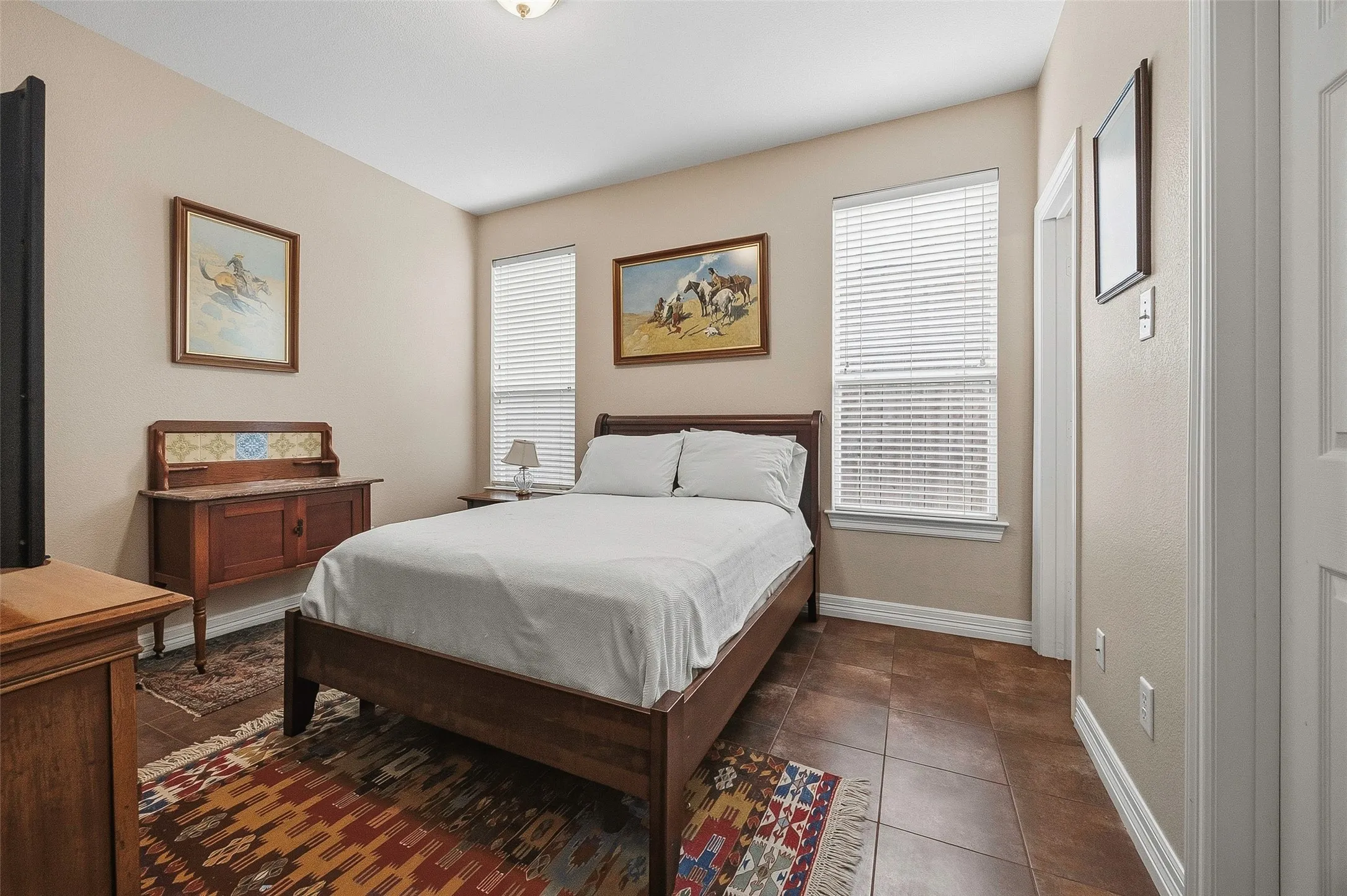 Tile flooring, two windows with blinds, light neutral wall paint, white trim, ceiling-mounted light fixture