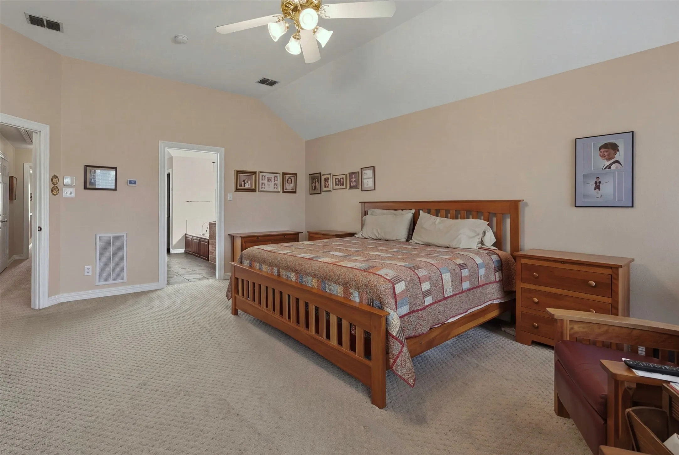 Vaulted ceiling with ceiling fan and light fixture, neutral-toned walls, and textured carpeting
