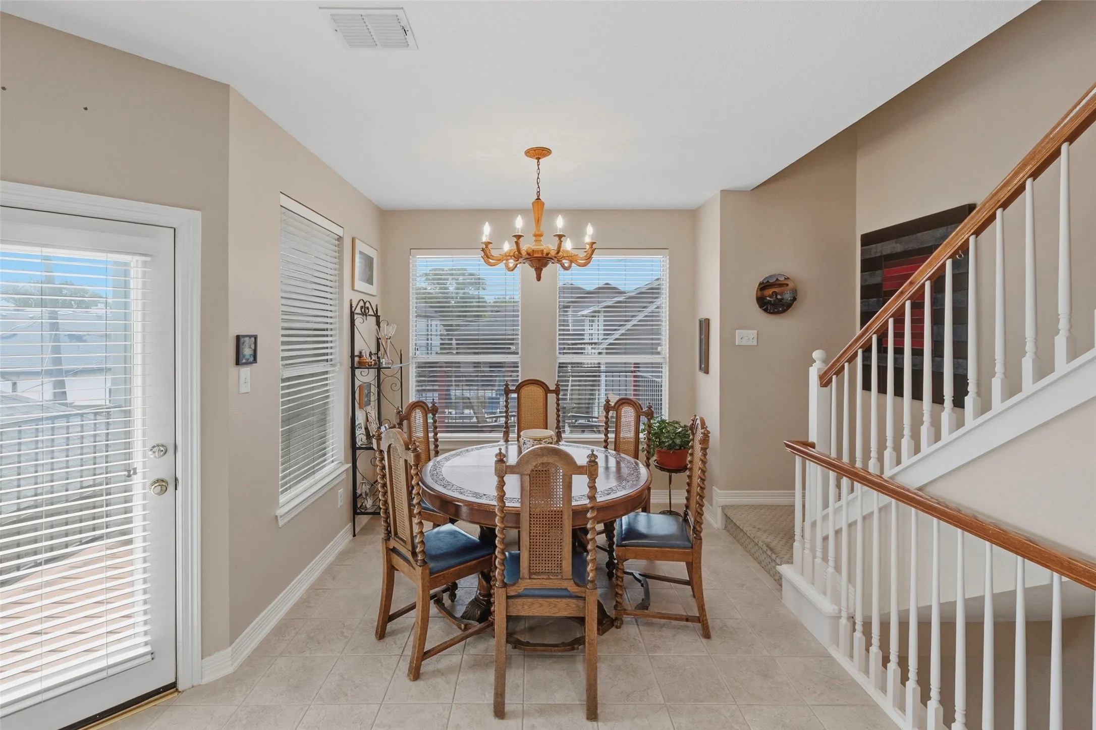 Ceramic tile flooring, white baluster staircase with wood handrail, recessed lighting, and multiple windows