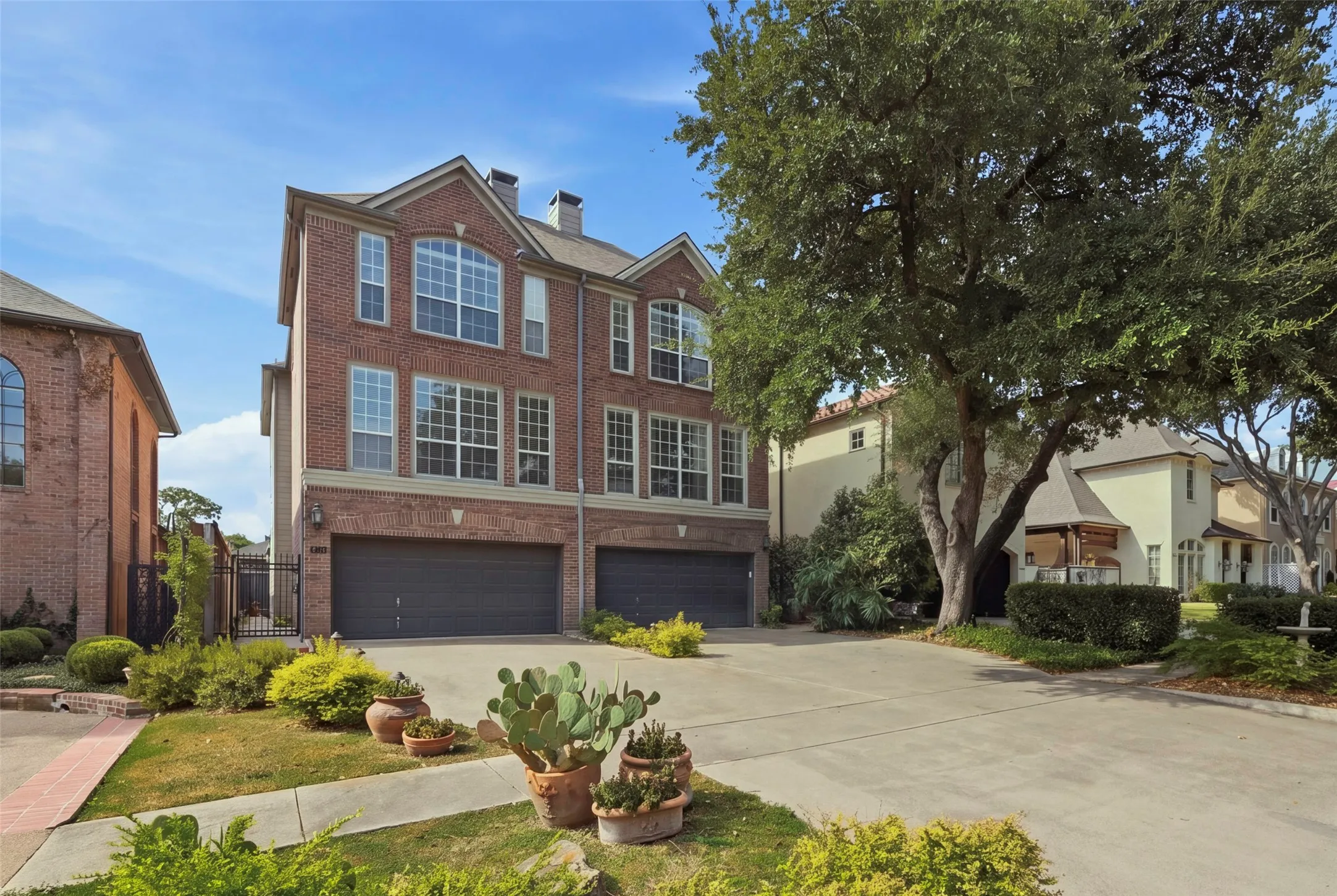 Brick exterior facade with multiple windows, an arched window, and two garages with dark doors