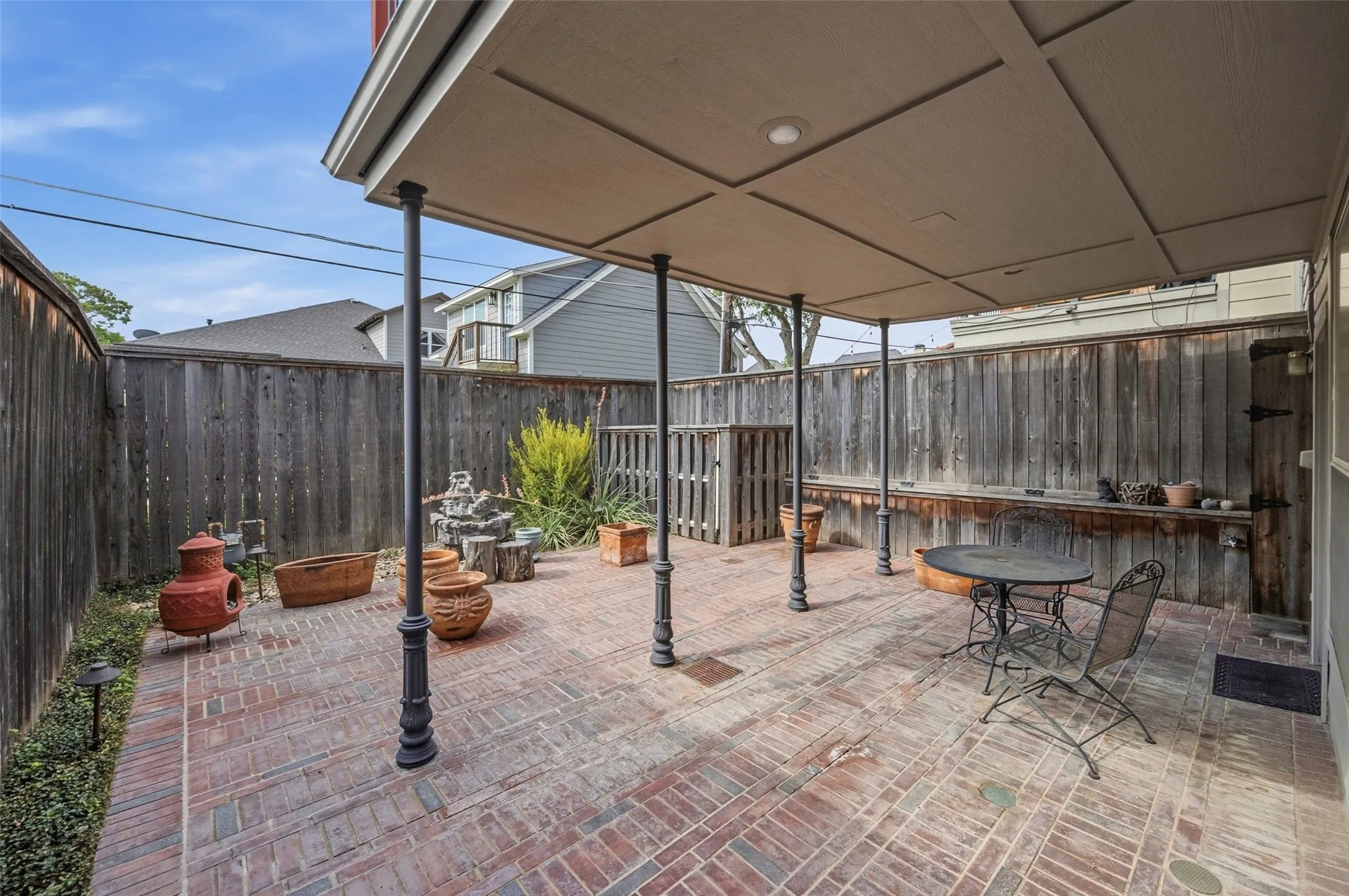Covered patio featuring brick paving, recessed lighting, and a built-in wooden counter