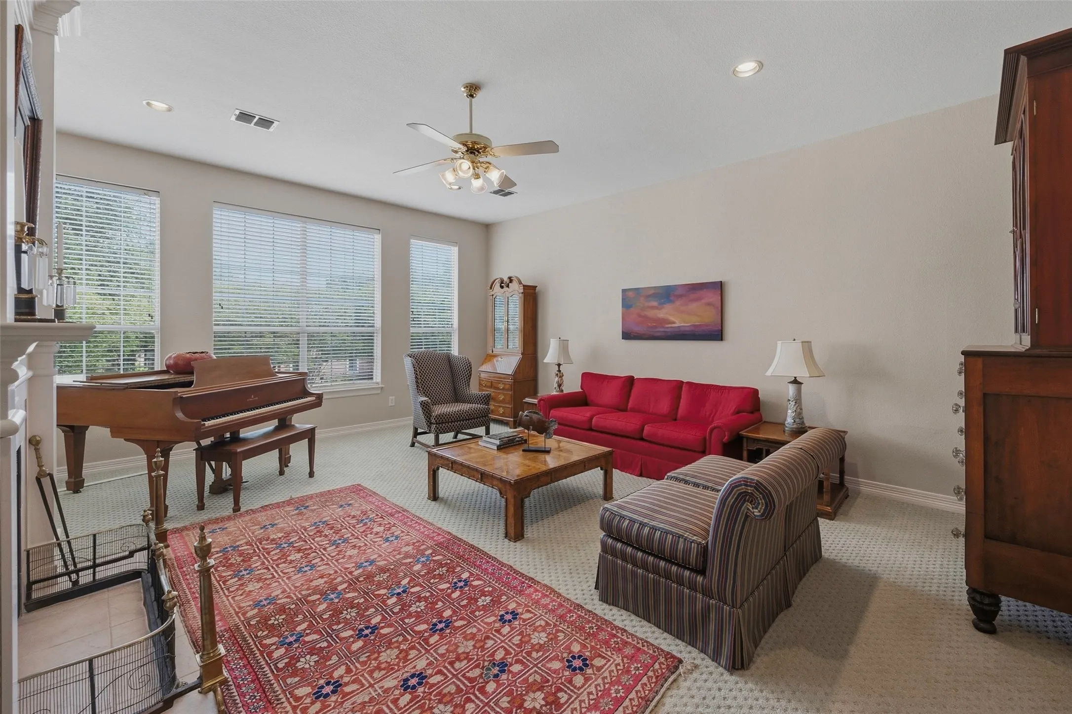 Recessed lighting, ceiling fan, multiple windows with blinds, and light-colored carpeting