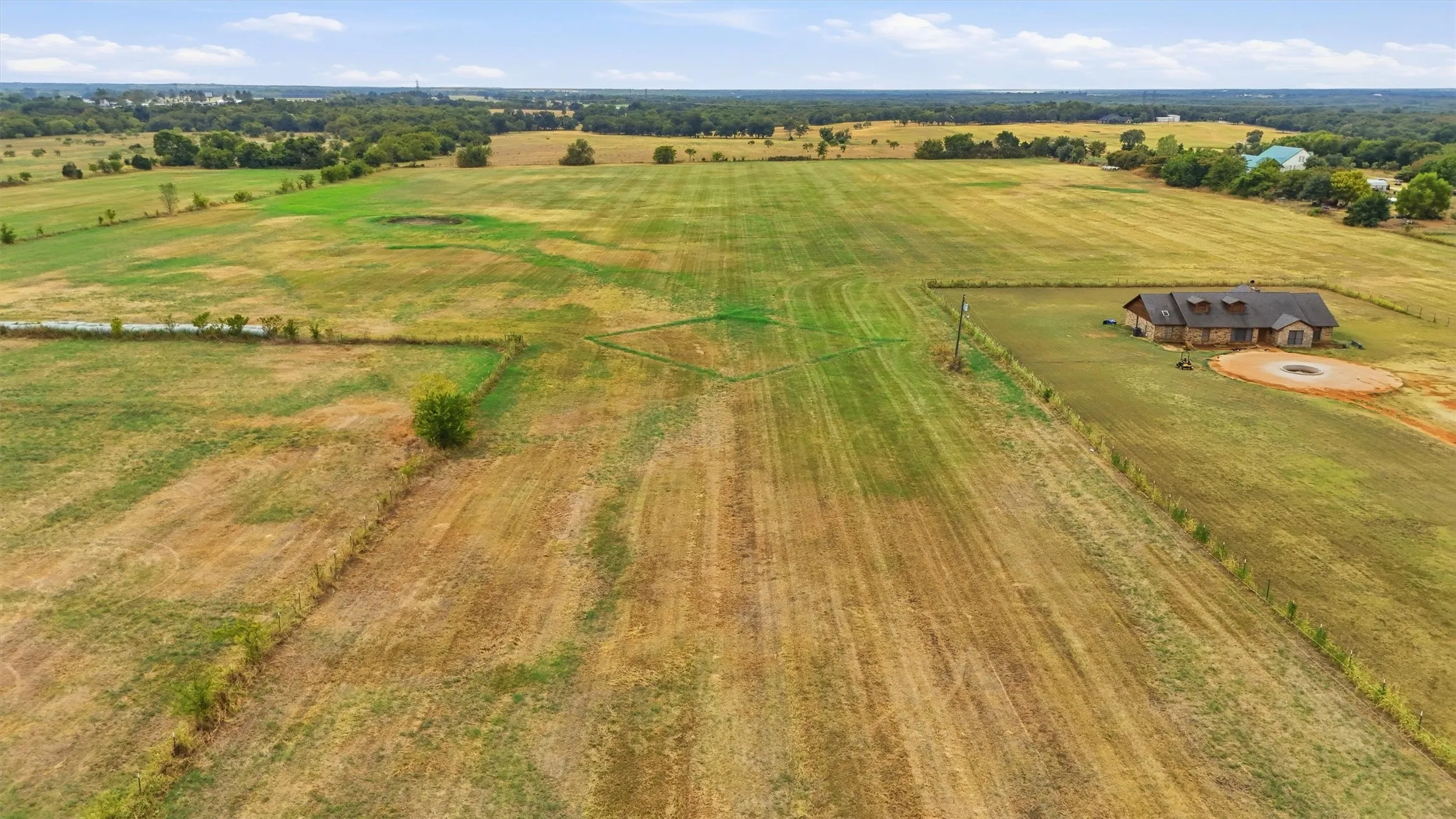 Extensive land parcel featuring open fields and a single-story residence with a stone exterior