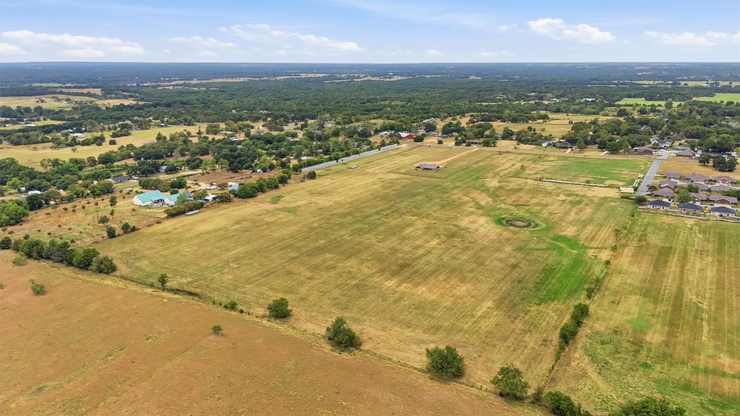 Expansive land parcel featuring open fields and mature perimeter trees