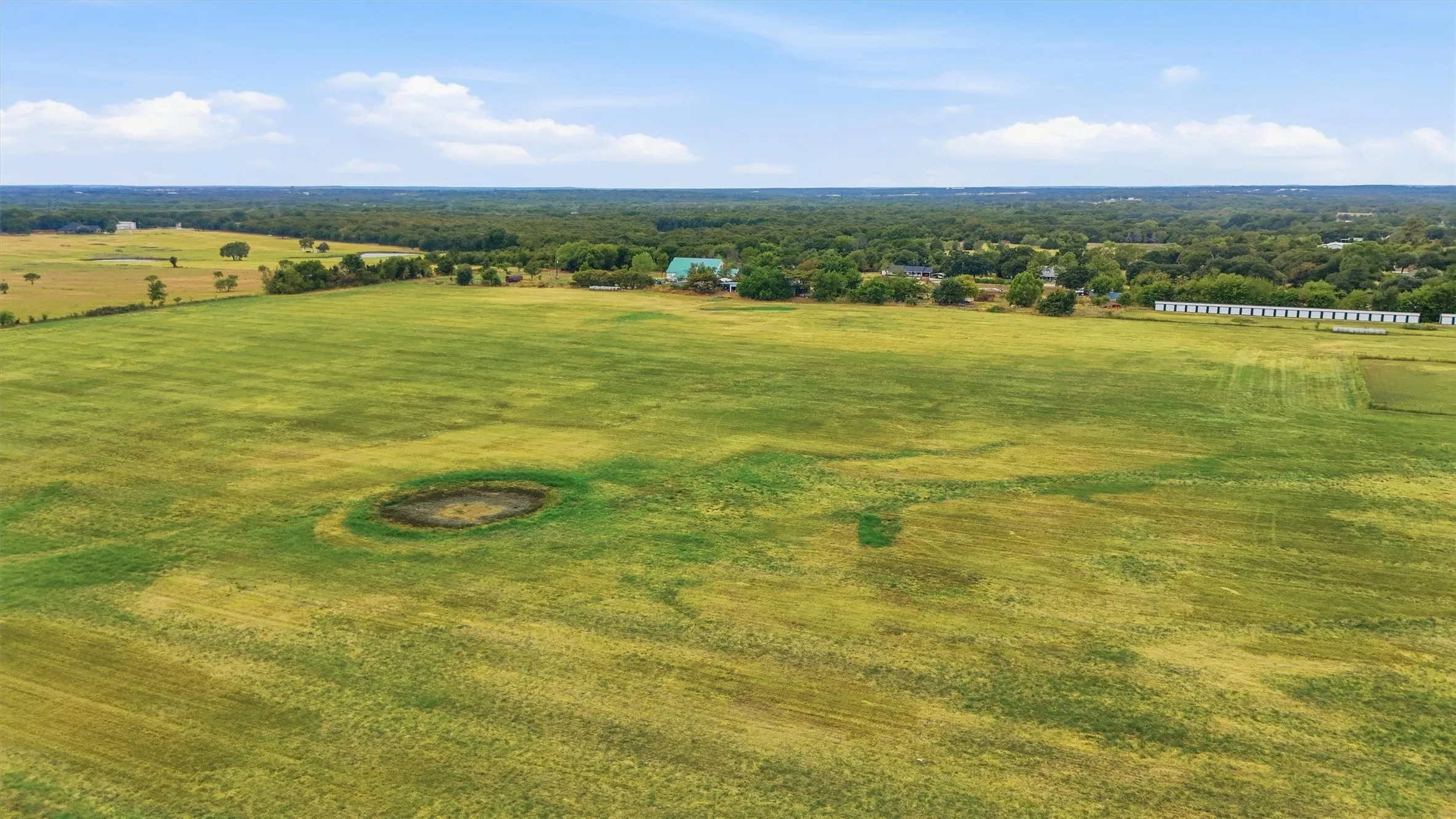 Expansive green acreage with a small pond
