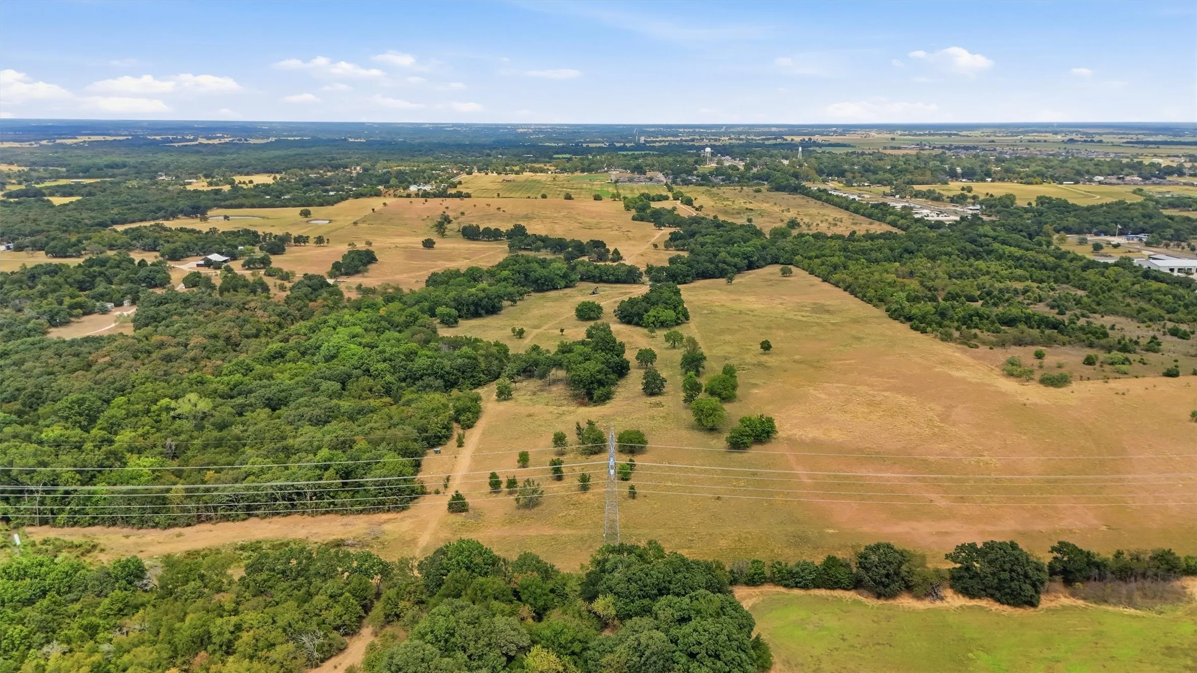 Expansive undeveloped land featuring a mix of open fields and mature tree coverage