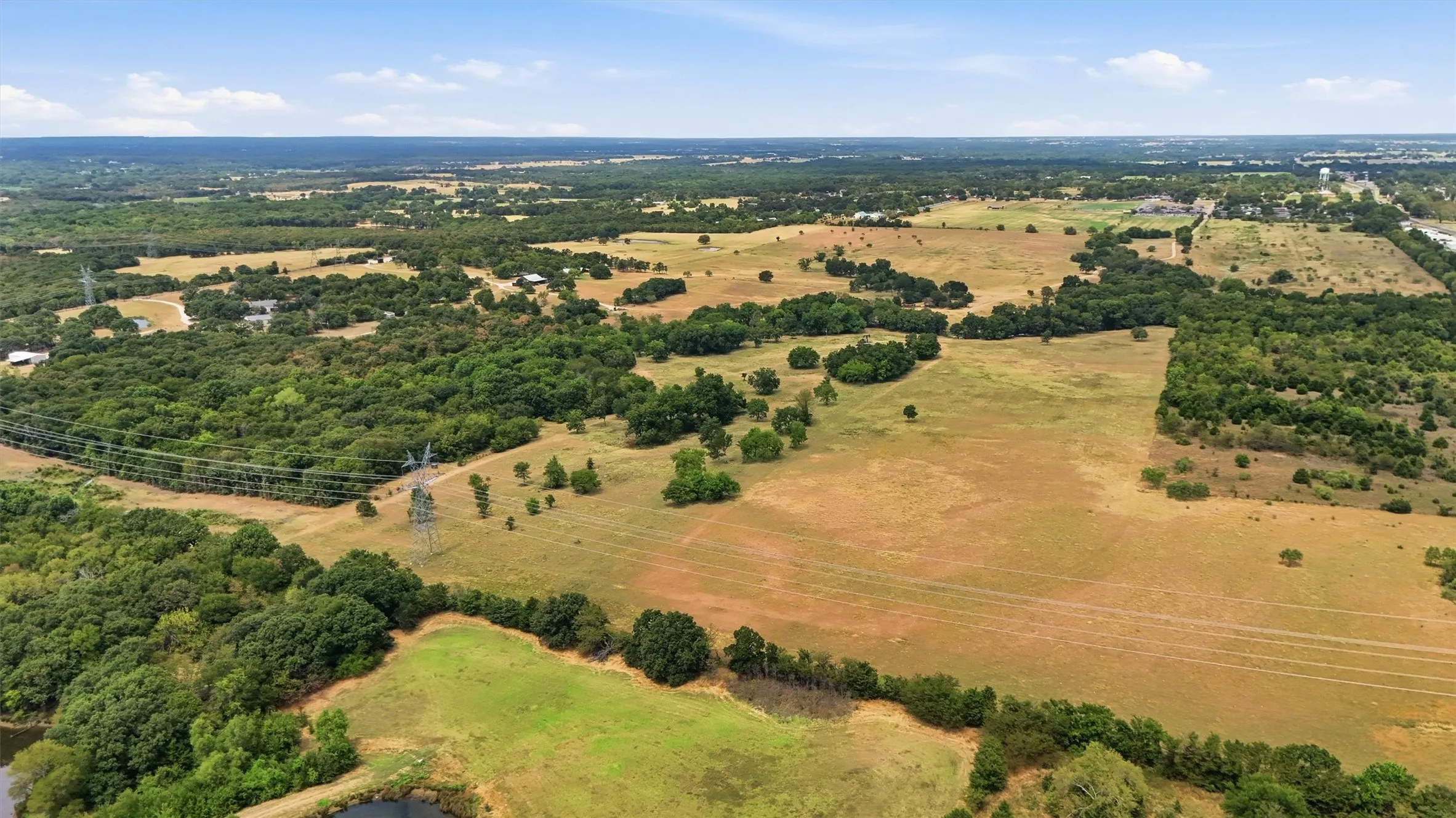 Expansive acreage featuring wooded areas, open fields, and a natural pond