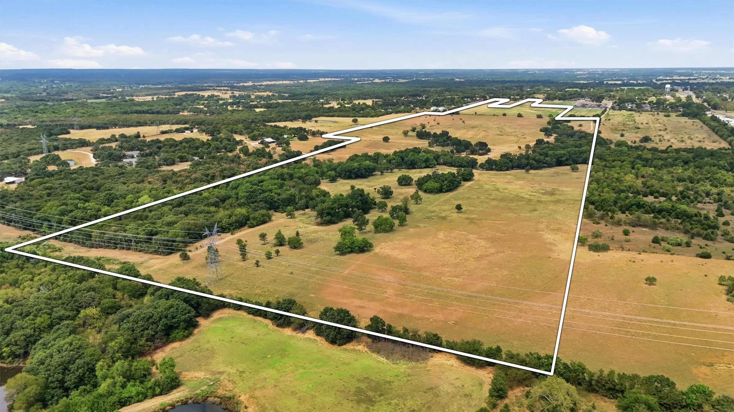 Expansive acreage featuring open fields, scattered mature trees, and natural wooded areas