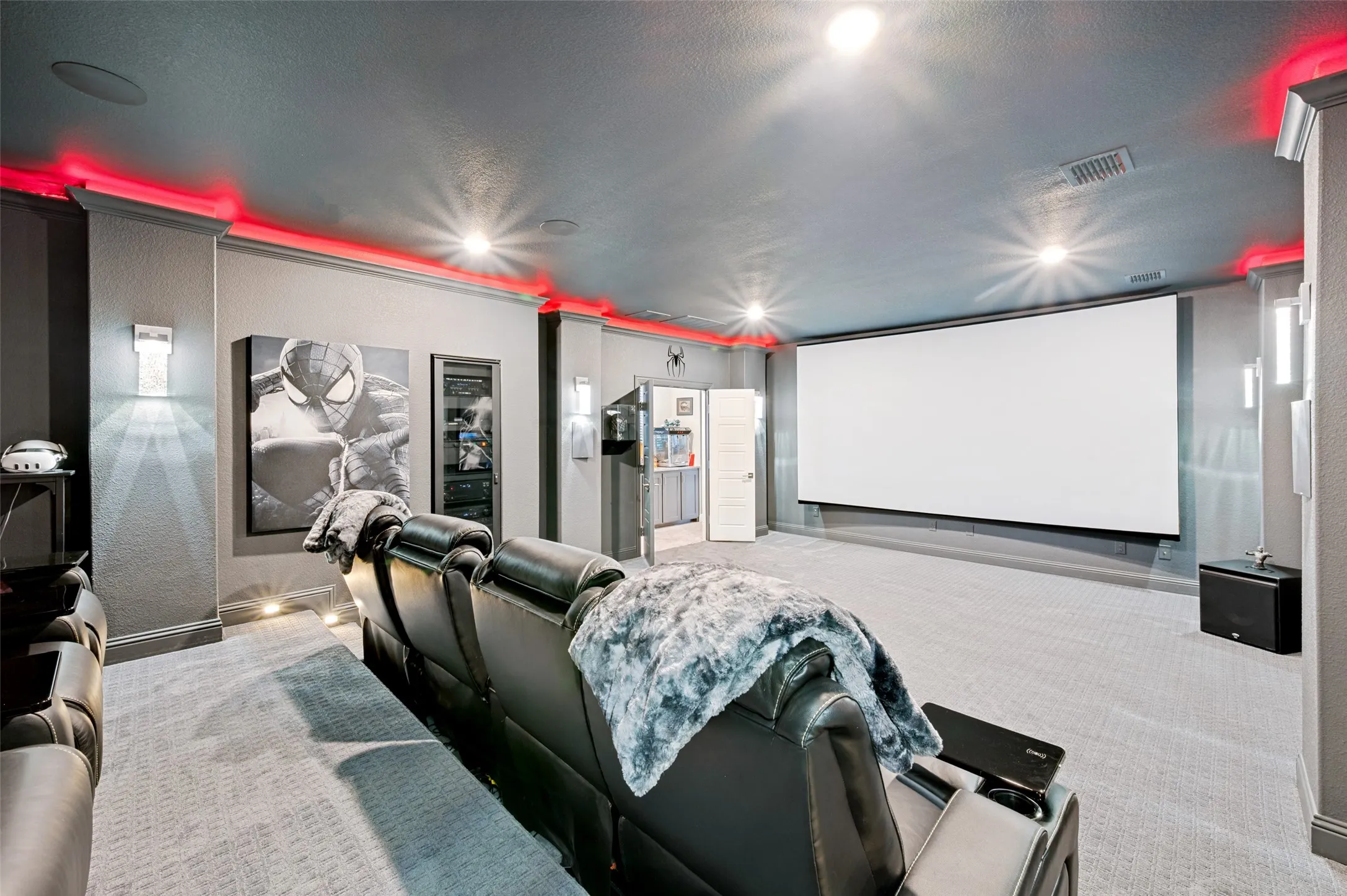 Home Theater featuring a large projection screen, tiered seating with upholstered recliners, accent lighting with red ambient strips, polished concrete flooring, and dedicated media equipment cabinetry