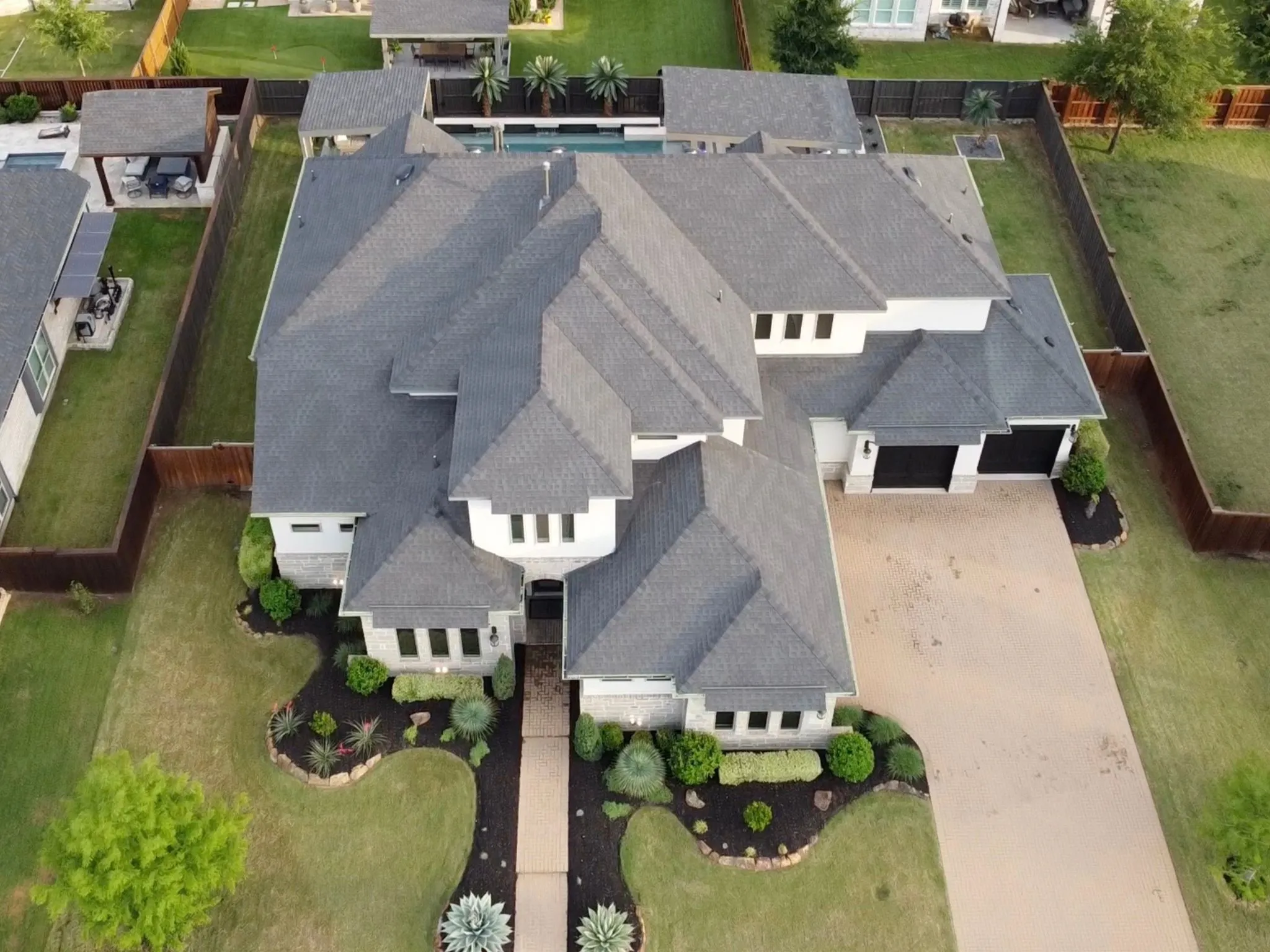 Expansive property with a multi-gabled roofline, stone and stucco exterior, an attached two-car garage, and a large paved driveway