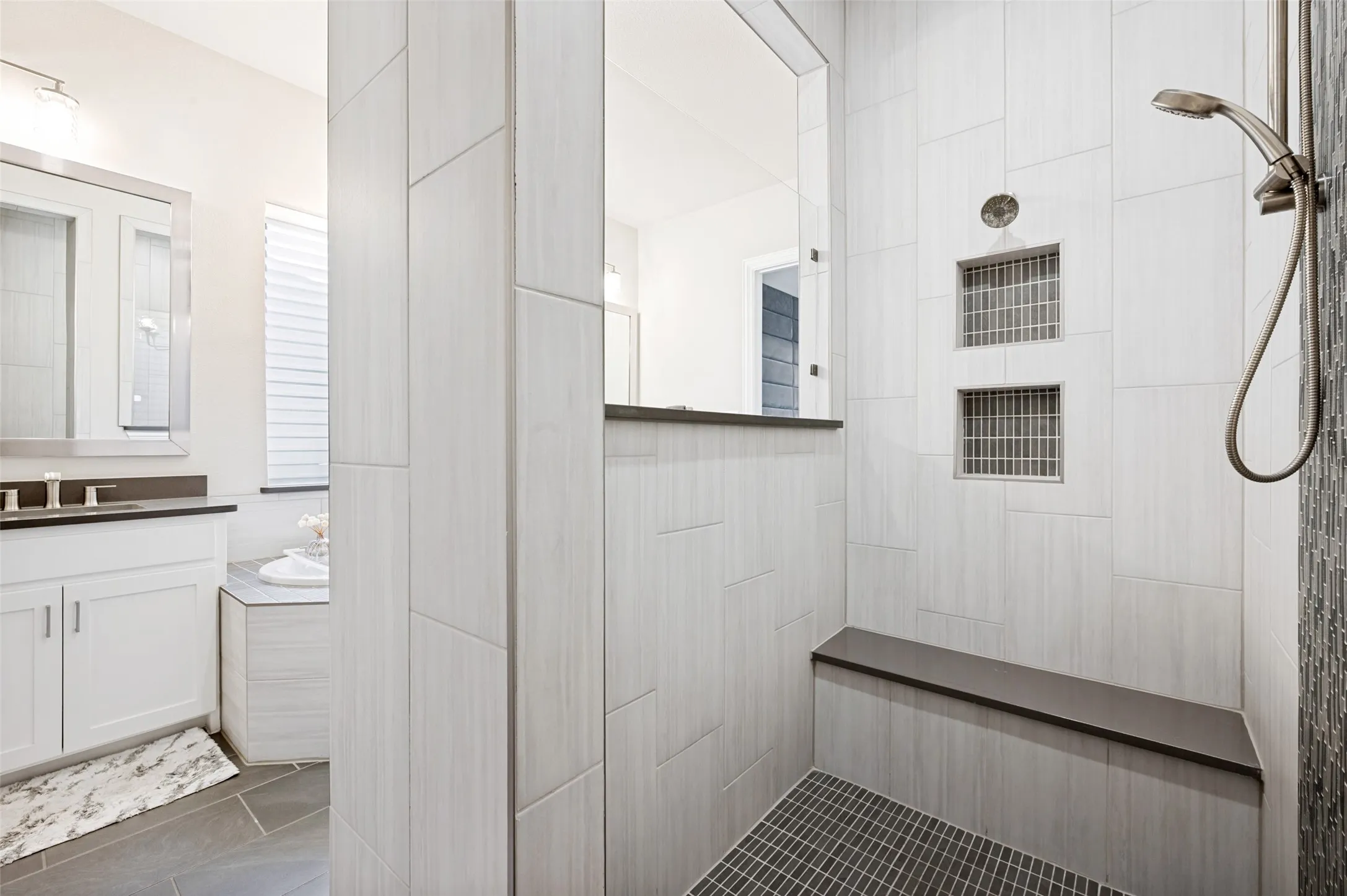 Walk-in shower with a built-in bench, dual recessed niches, and a handheld shower fixture