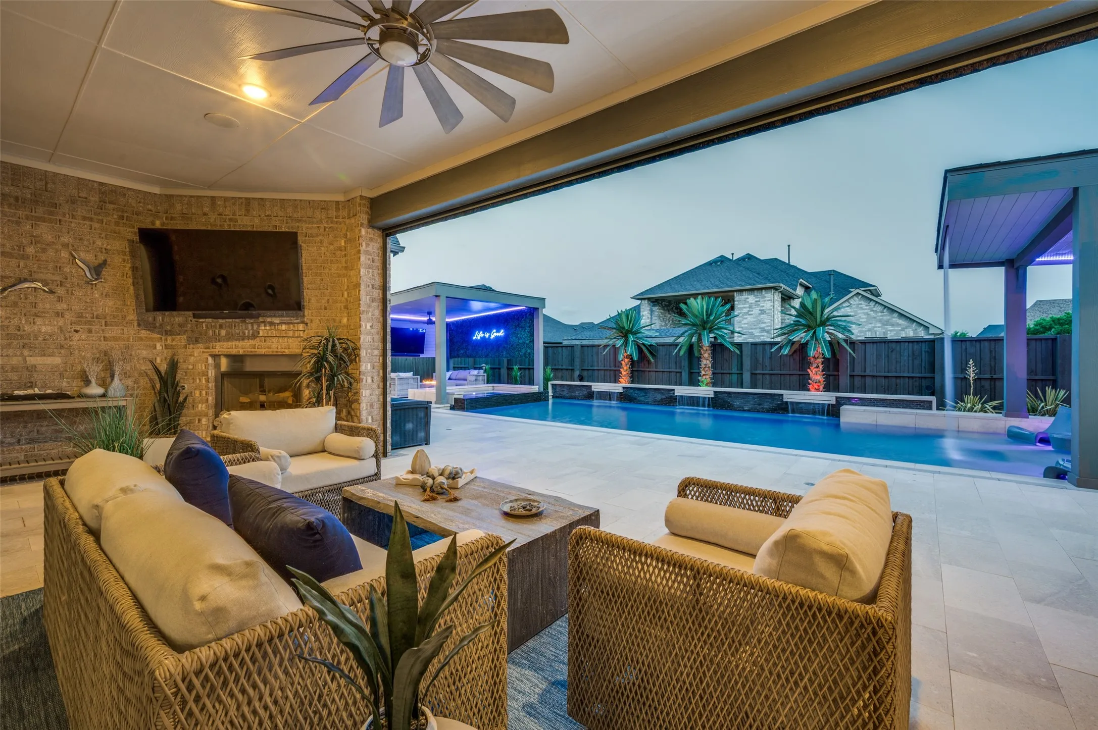 Expansive outdoor living area with a built-in fireplace and ceiling fan