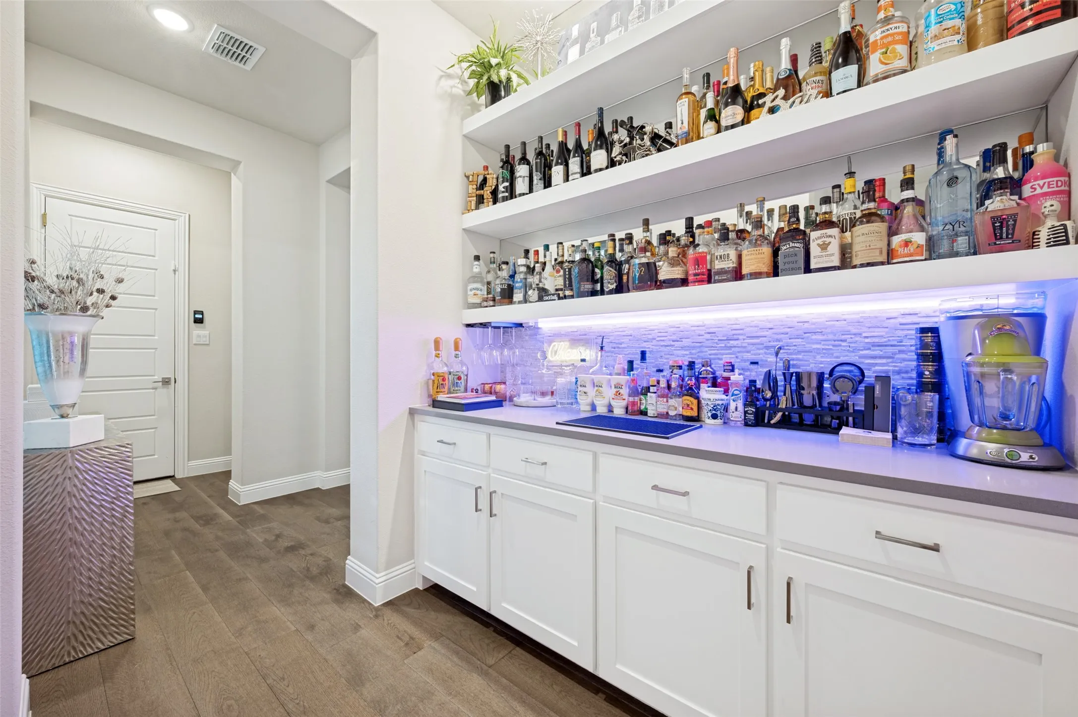 Built-in cabinetry with a light-toned countertop, open shelving, and integrated lighting