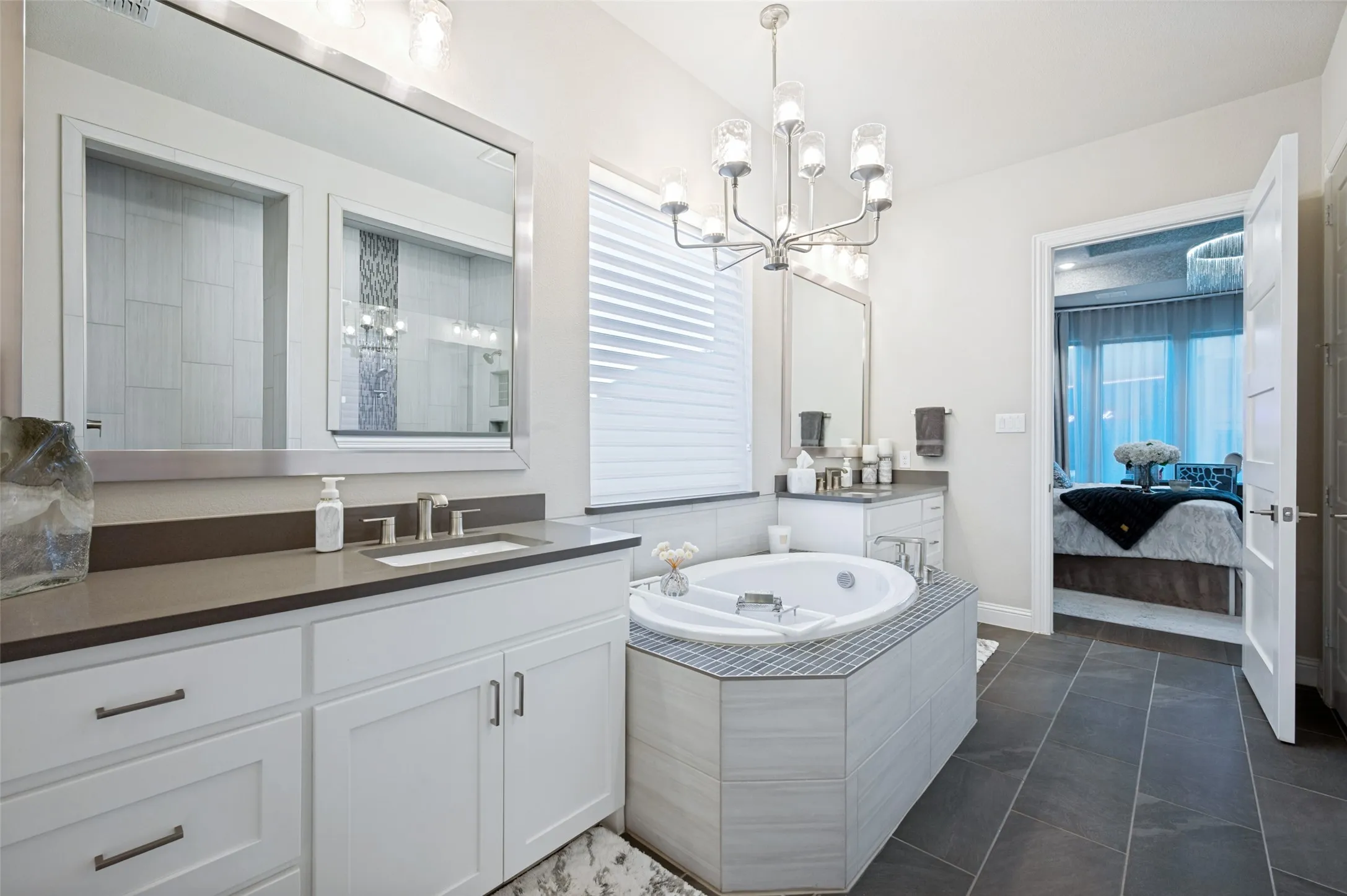 Dual vanity with integrated sinks, built-in soaking tub, chandelier lighting, and a separate walk-in shower