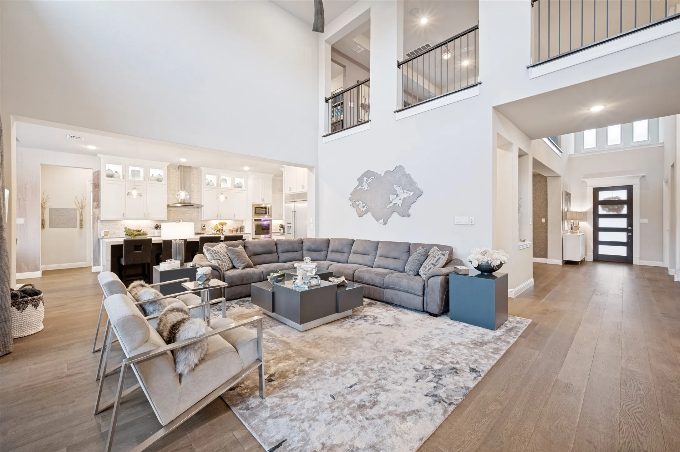 Two-story living area with wood-finish flooring, an open-concept kitchen, and upper-level interior balconies