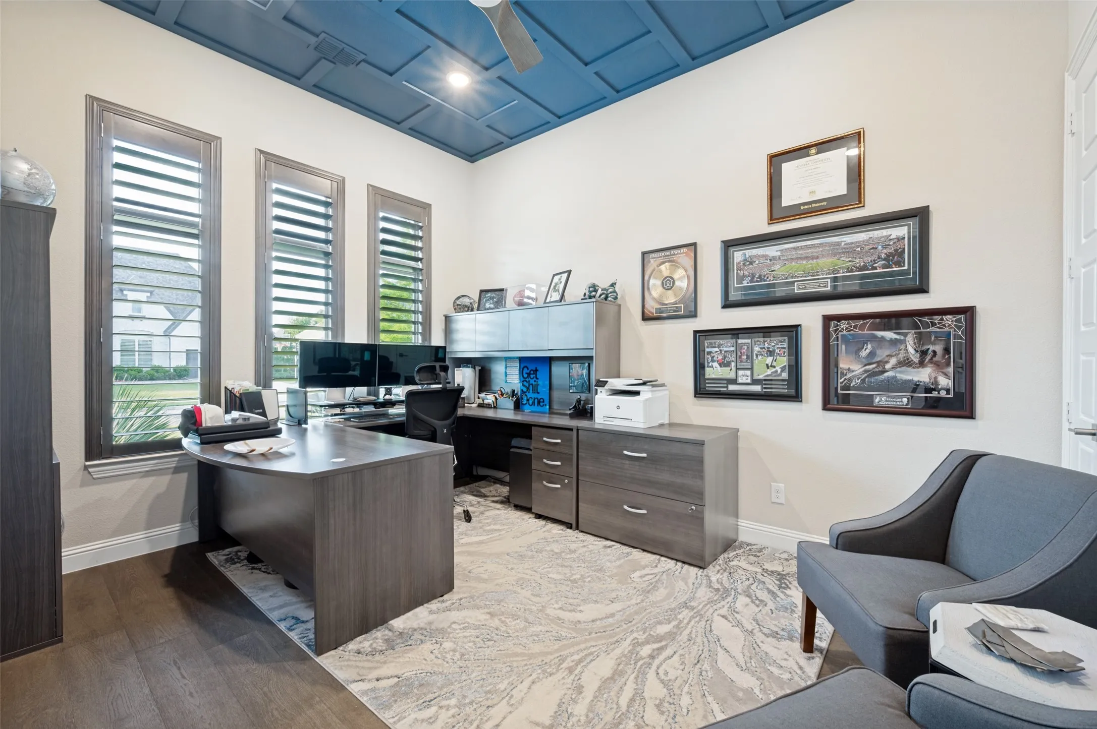 Wood-finish flooring with a contrasting ceiling, three tall windows with louvered shutters, and recessed lighting