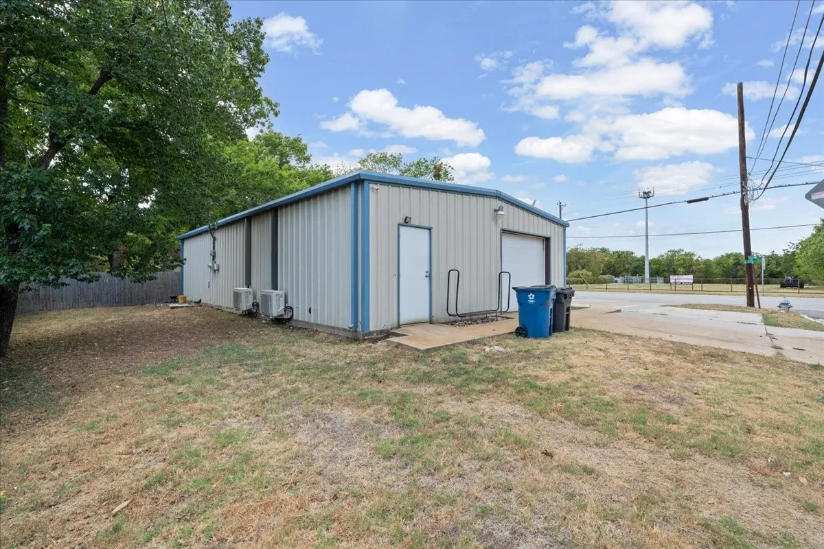 Metal-sided structure featuring a pedestrian entry door, a roll-up garage door, and multiple exterior HVAC units