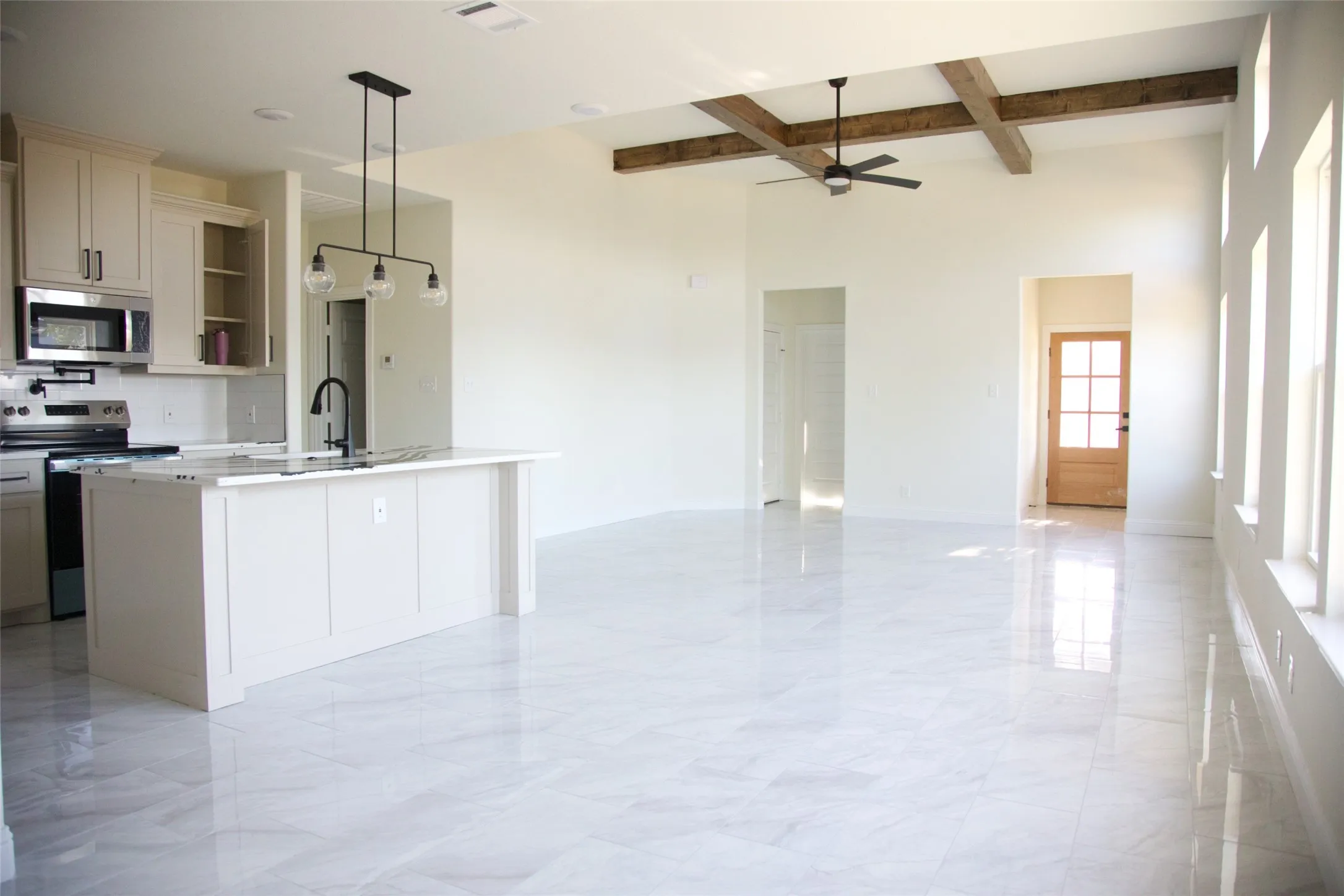 Open-concept living space with high ceilings, exposed wood beams, and large windows