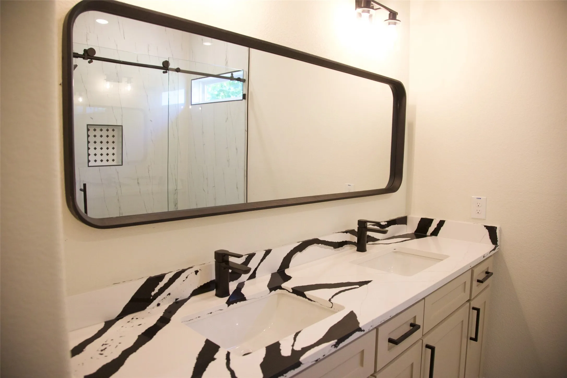 Double vanity with black and white patterned countertop, matte black faucets, and undermount sinks
