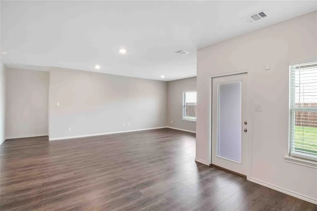 Empty room with a wealth of natural light and dark hardwood / wood-style flooring