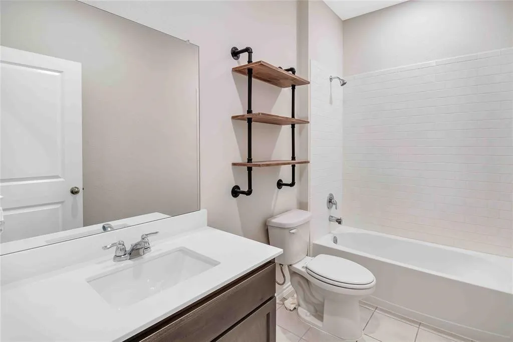 Full bathroom featuring toilet, tiled shower / bath, vanity, and tile patterned flooring