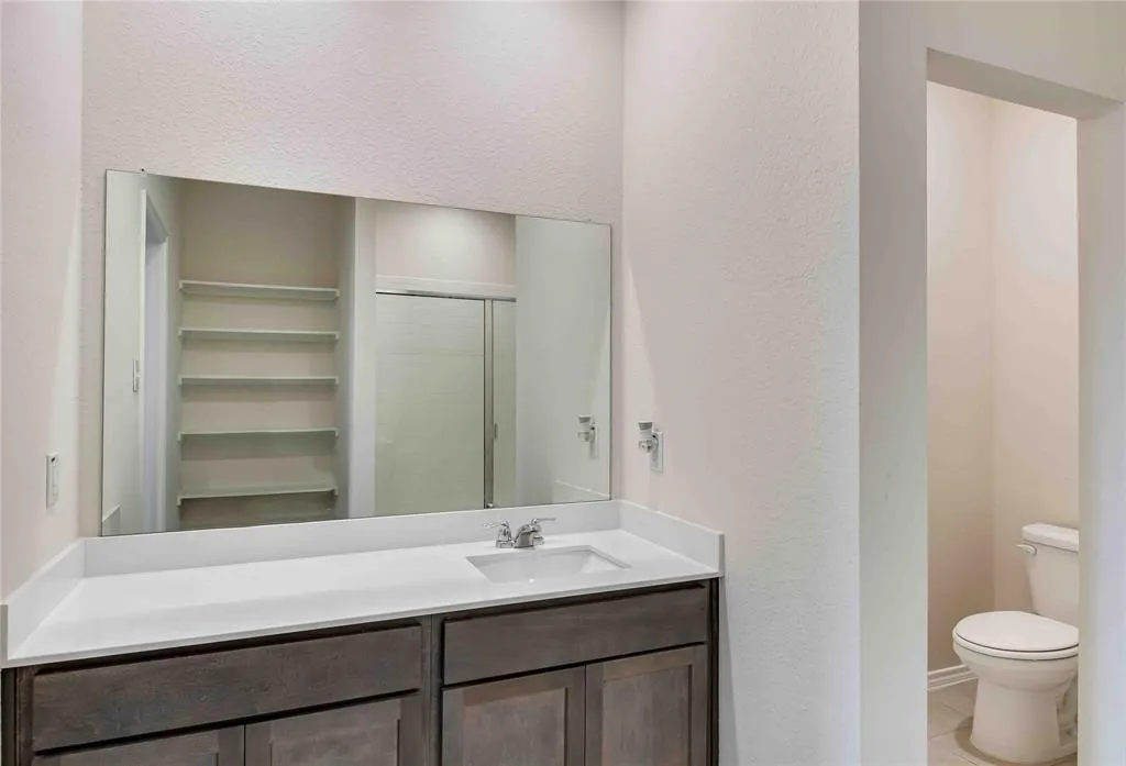 Bathroom featuring vanity, toilet, tile patterned floors, and an enclosed shower