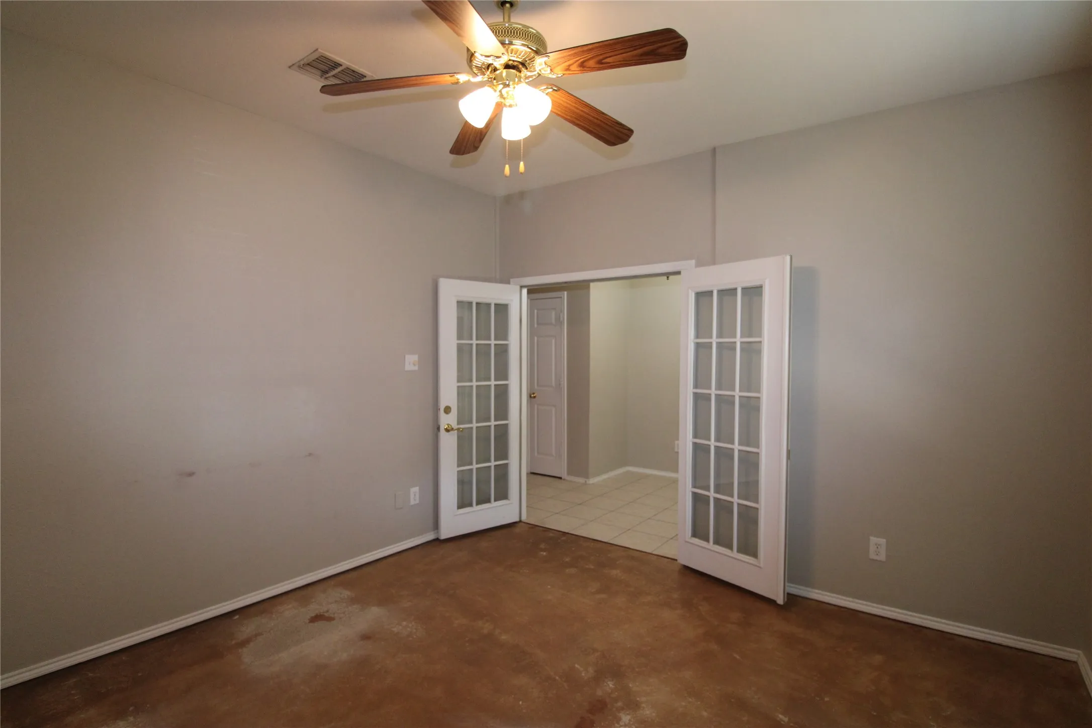 French doors with glass paneling, overhead ceiling fan with light fixture, and tile flooring in the adjacent space