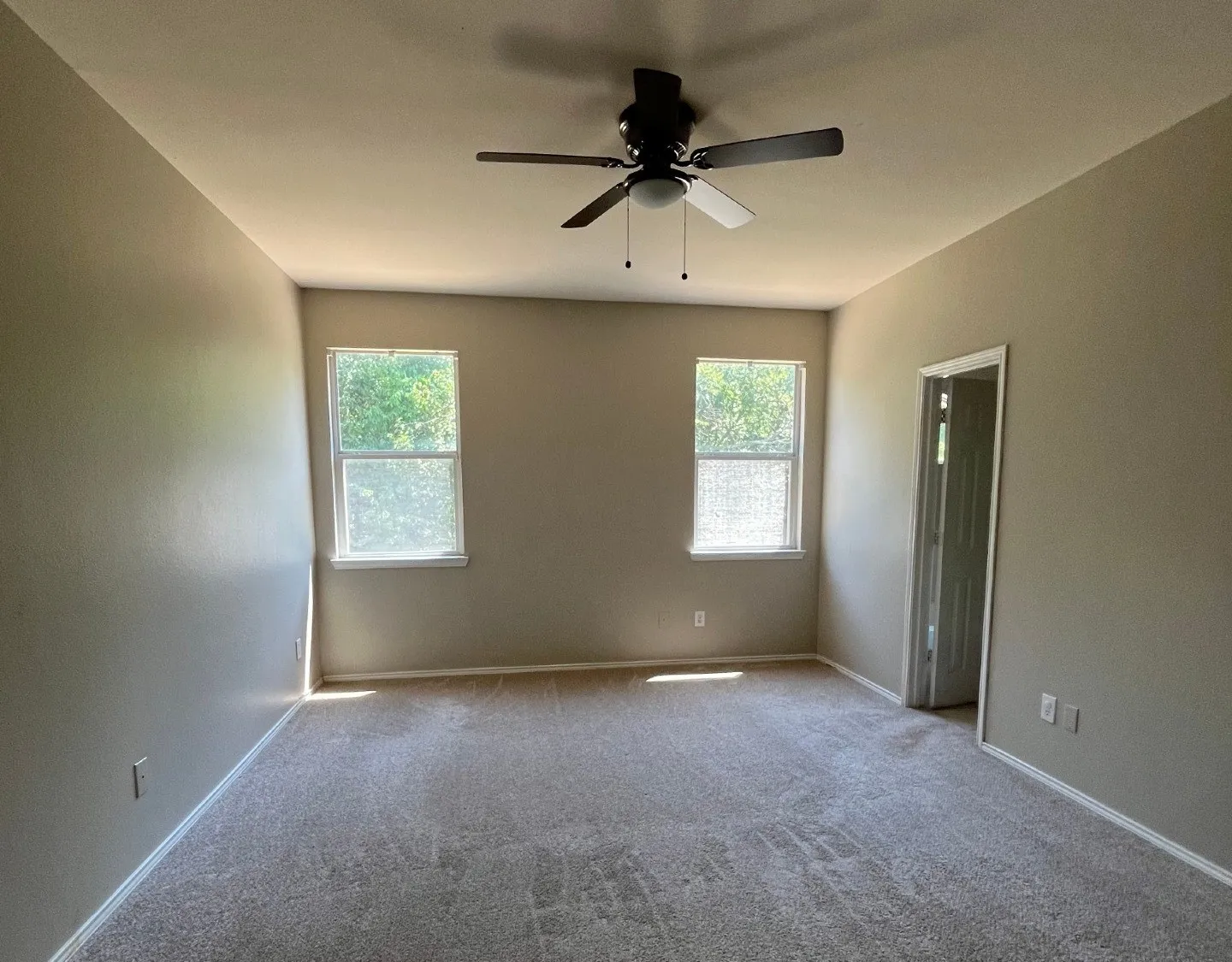 Neutral tone walls, carpet flooring, and a ceiling fan with integrated lighting