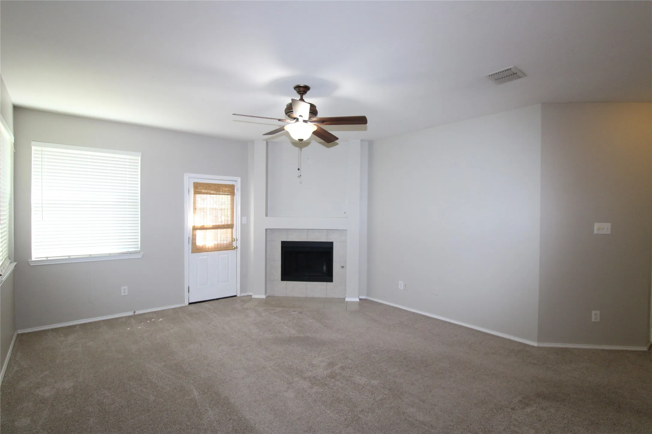 Neutral-toned carpet flooring, fireplace with tile surround, white trim, and a ceiling fan with integrated​​‌​​​​‌​​‌‌​‌‌​​​‌‌​‌​‌​‌​​​‌​​ lighting