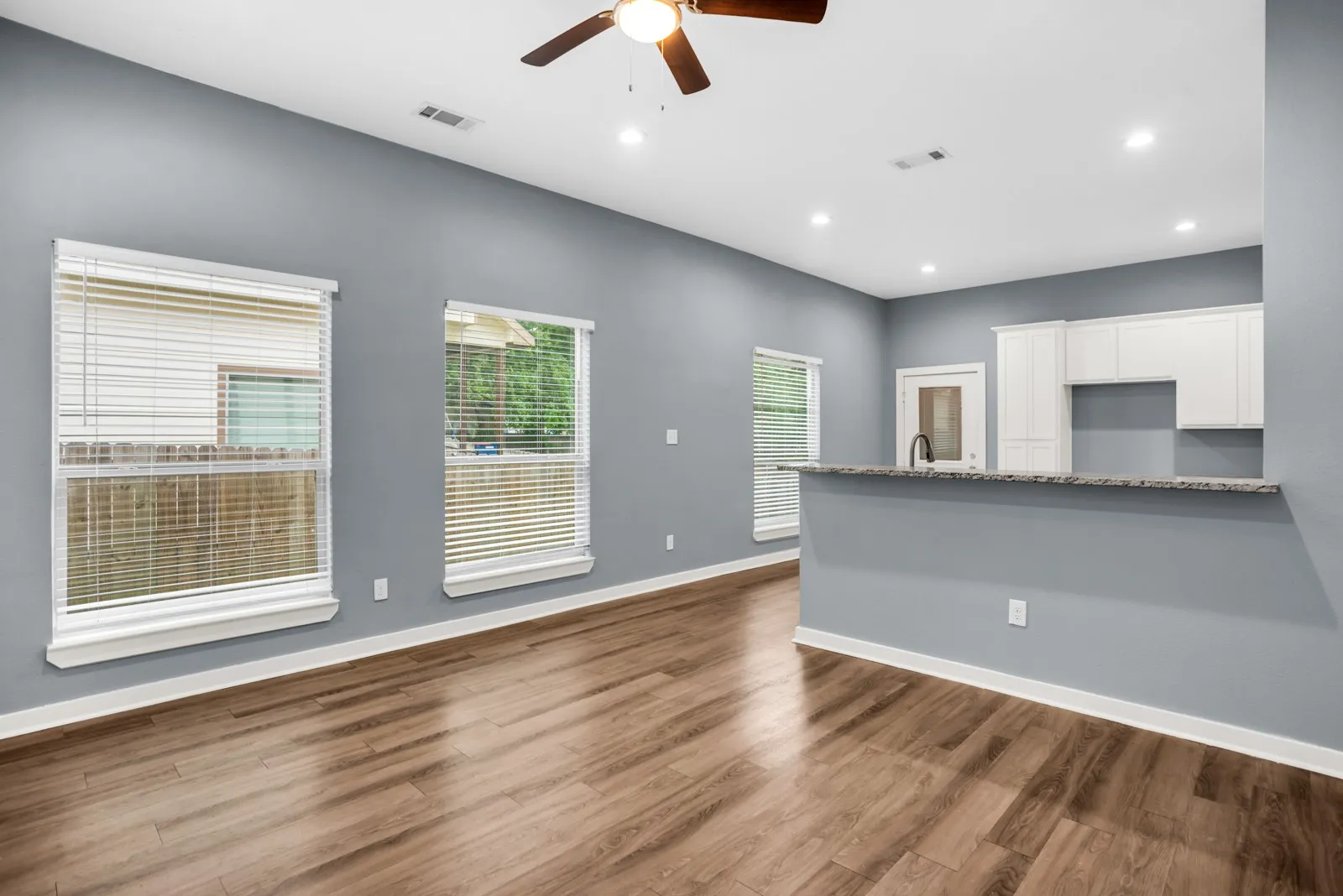 Open-concept living area featuring wood-finish flooring, recessed lighting, and a ceiling fan