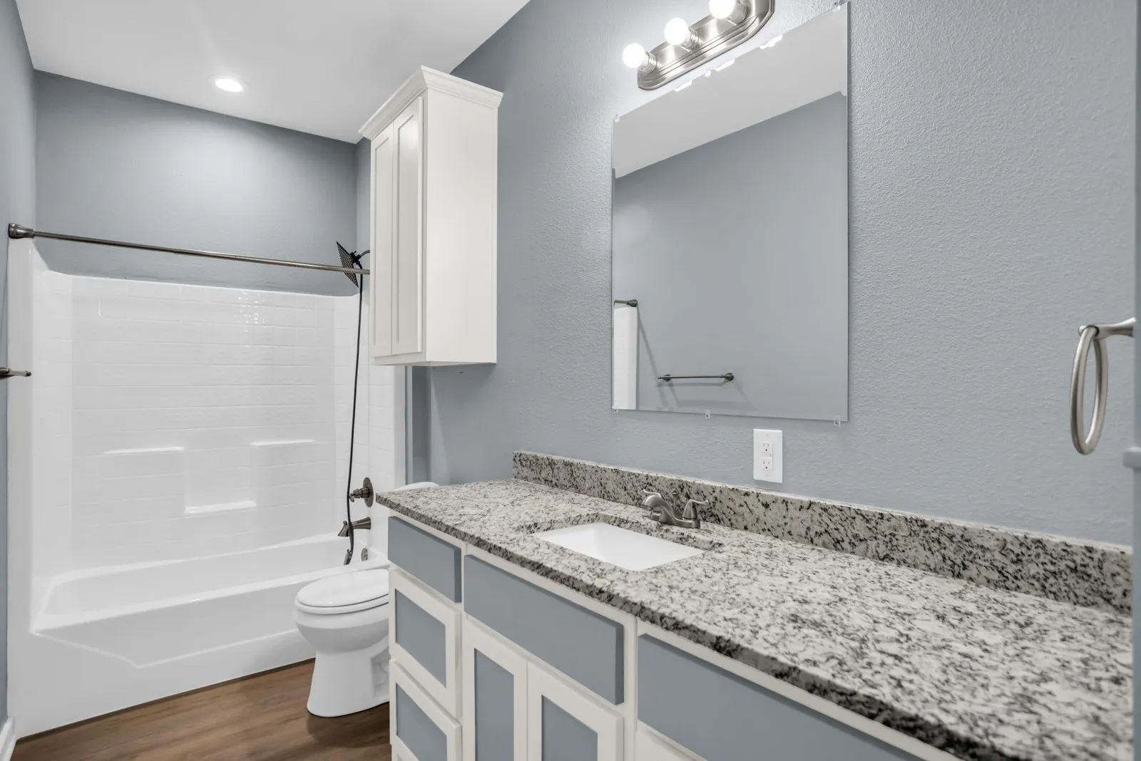 Bathroom featuring a spacious vanity with a granite countertop, undermount sink, and a framed mirror