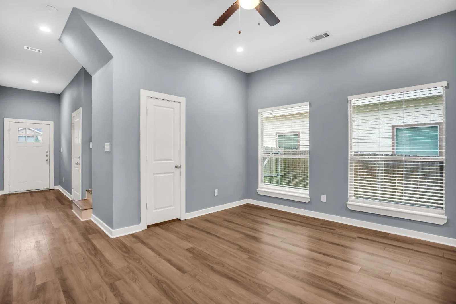 Spacious room with wood-finish flooring, light blue walls, and white trim