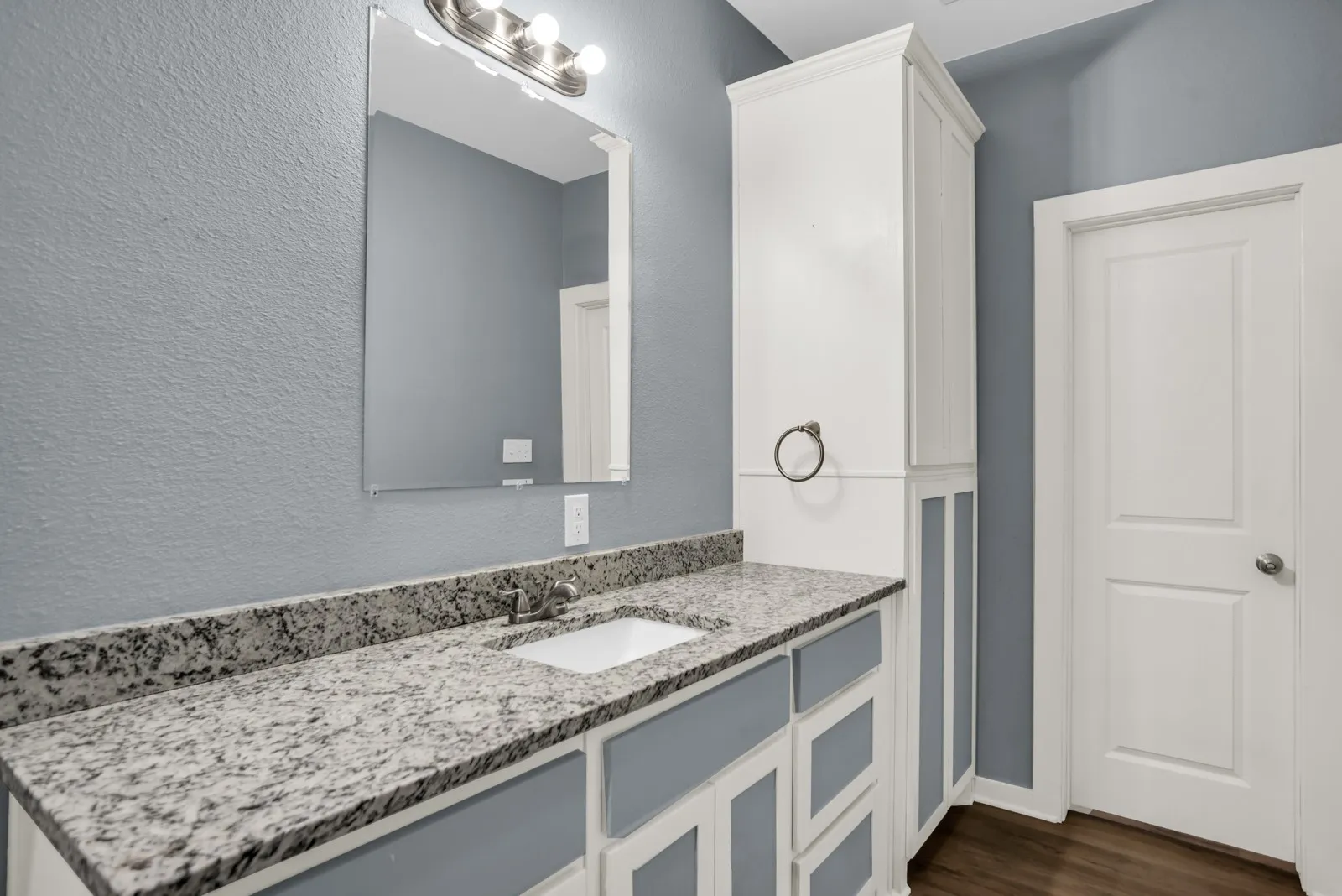 Bathroom vanity featuring a speckled countertop, undermount sink, and brushed nickel faucet