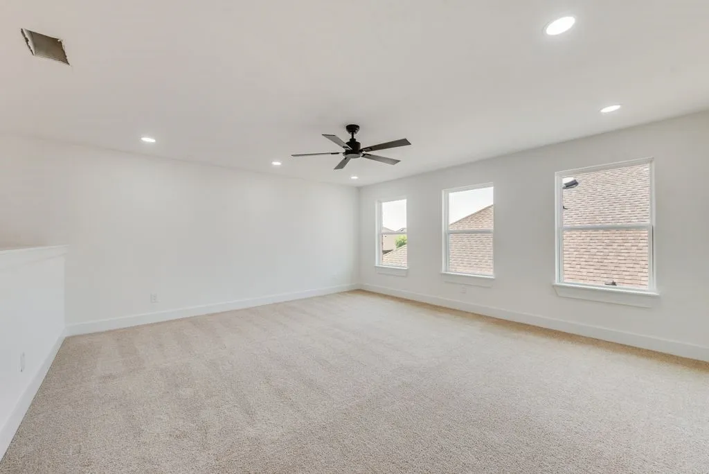 Bright, light-filled room with multiple windows offering natural illumination, neutral wall finishes, and neutral carpet flooring