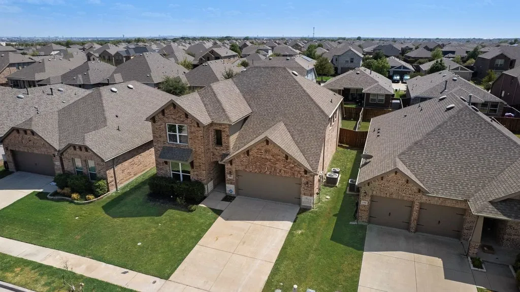 Two-story brick exterior with an attached garage, paved driveway, and established landscaping