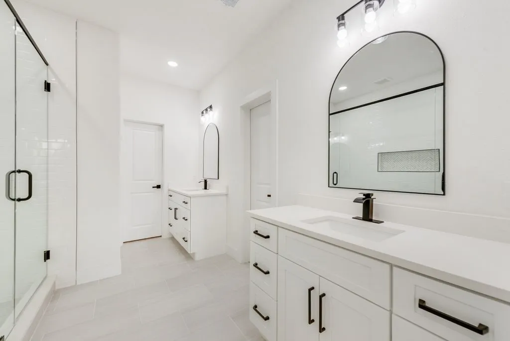 Dual vanities with white cabinetry, integrated sinks, and contemporary matte black fixtures