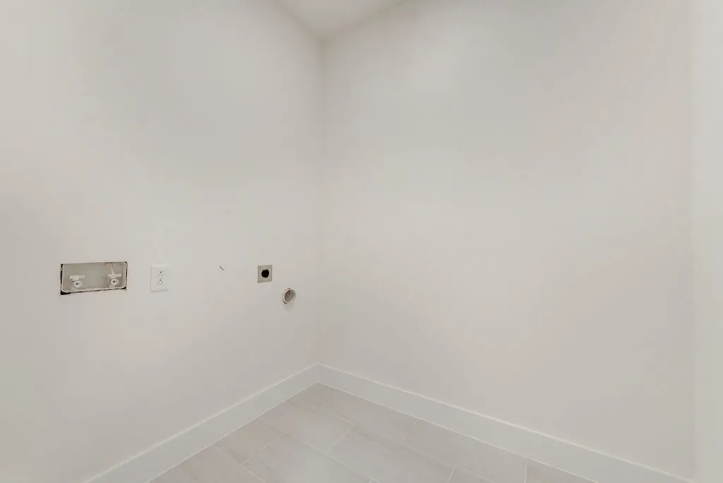 Light-toned wall finish, tile flooring, and utility hookups for appliances